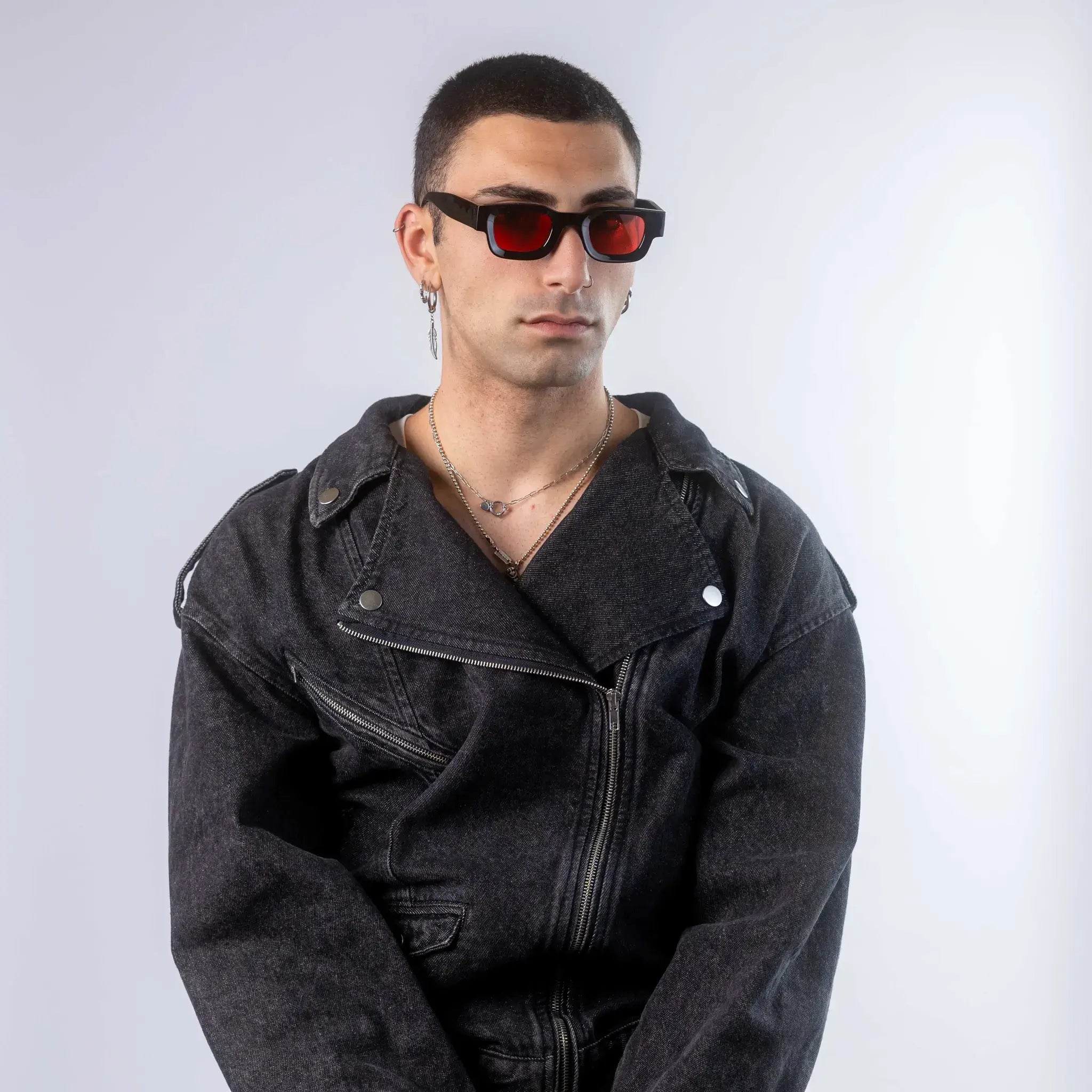 A male model wearing Exposure Sunglasses polarized sunglasses with black frames and red lenses, posing against a white background.