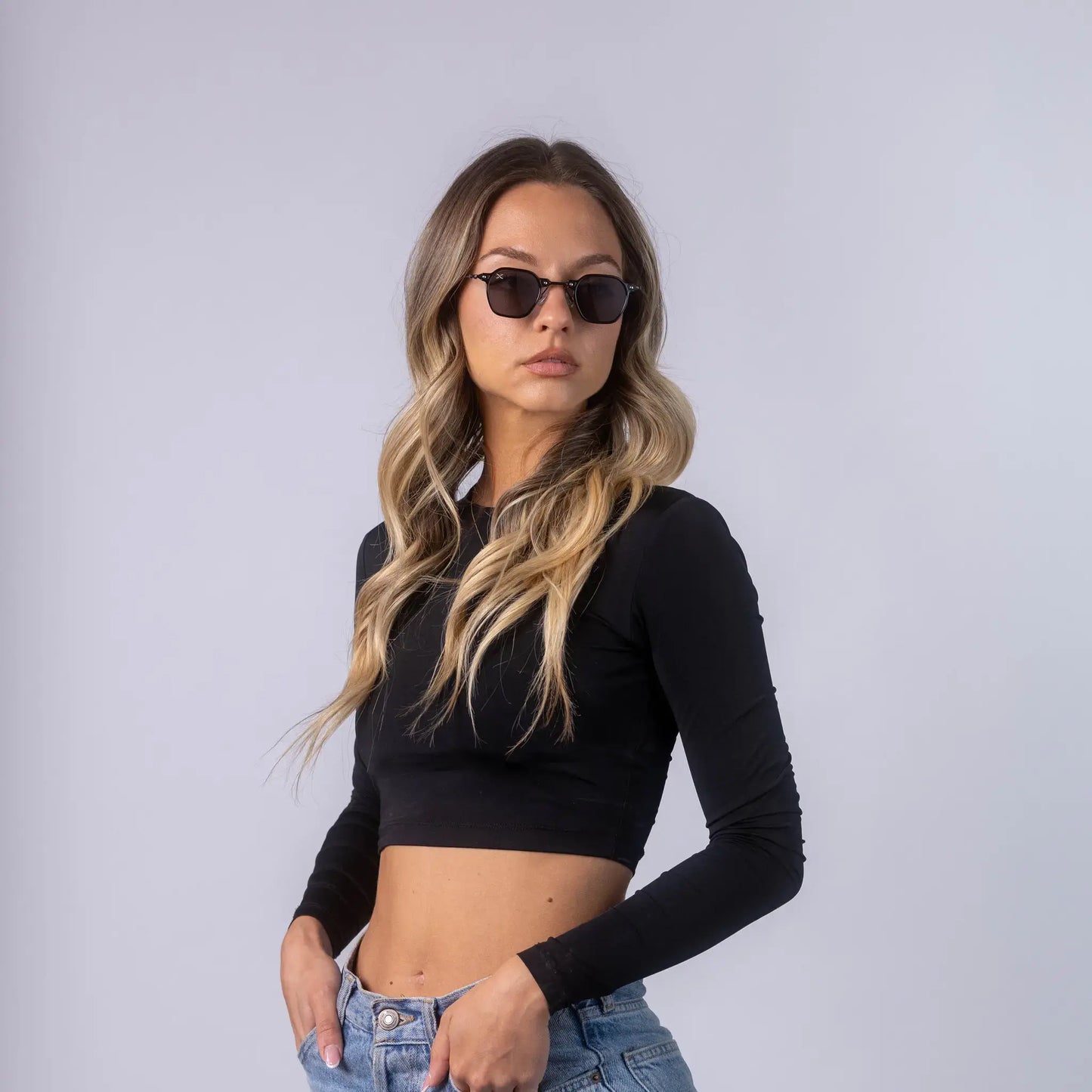 A female model wearing Exposure Sunglasses polarized sunglasses with black frames and black lenses, posing against a white background.