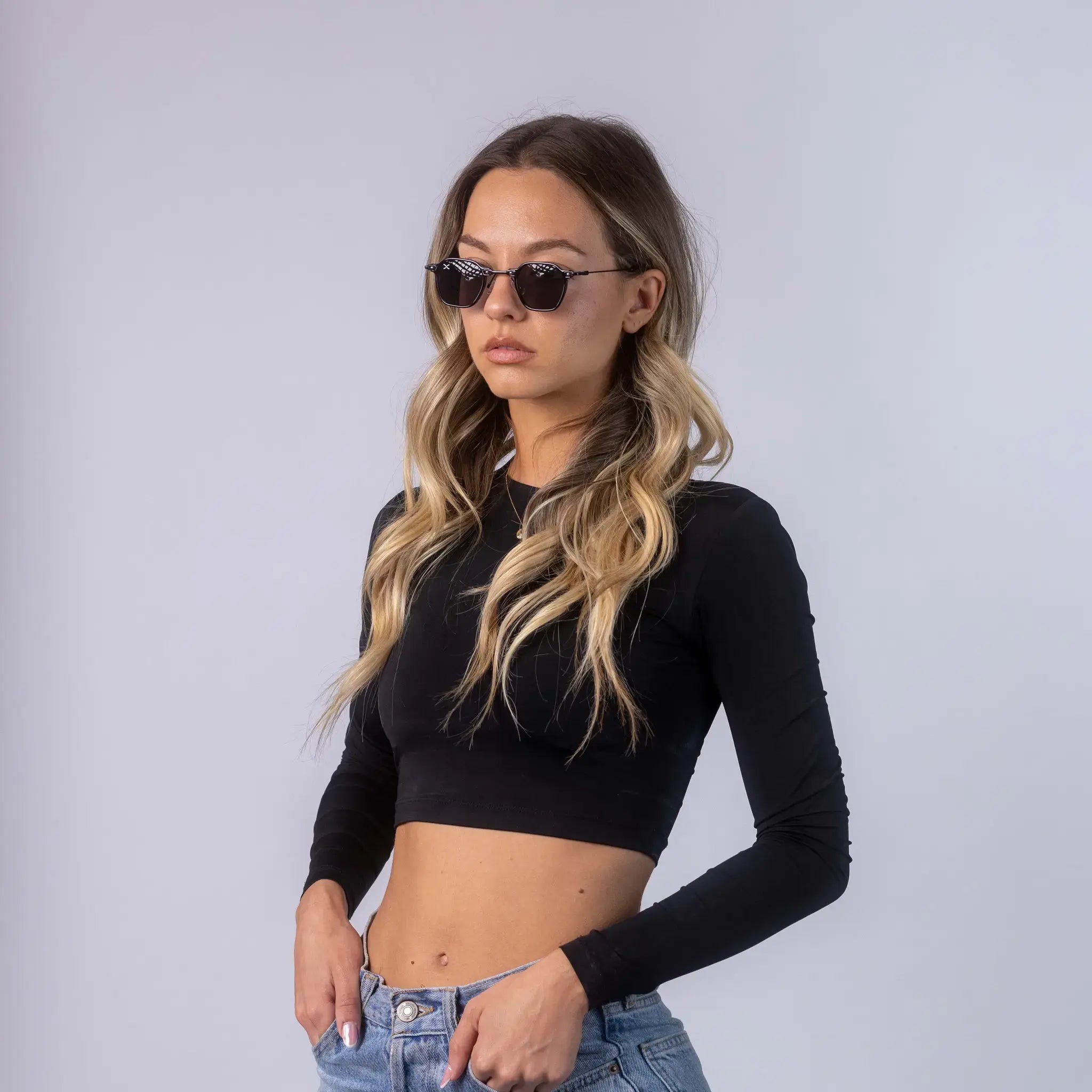 A female model wearing Exposure Sunglasses polarized sunglasses with black frames and black lenses, posing against a white background.