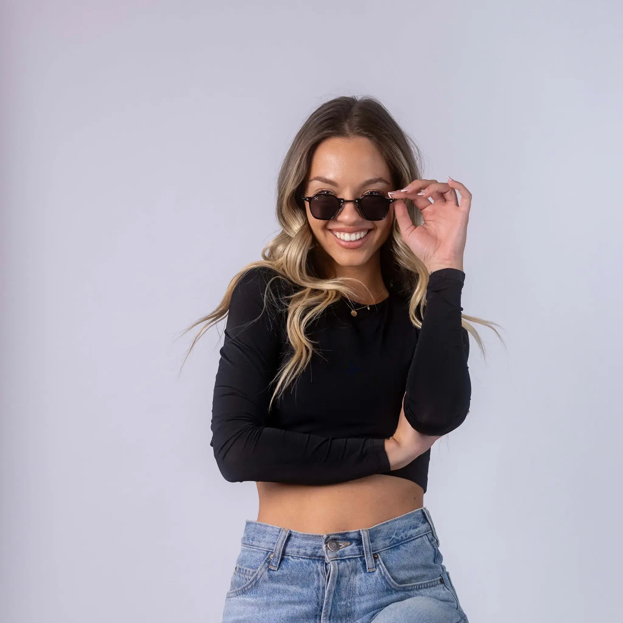 A female model wearing Exposure Sunglasses polarized sunglasses with black frames and black lenses, posing against a white background.