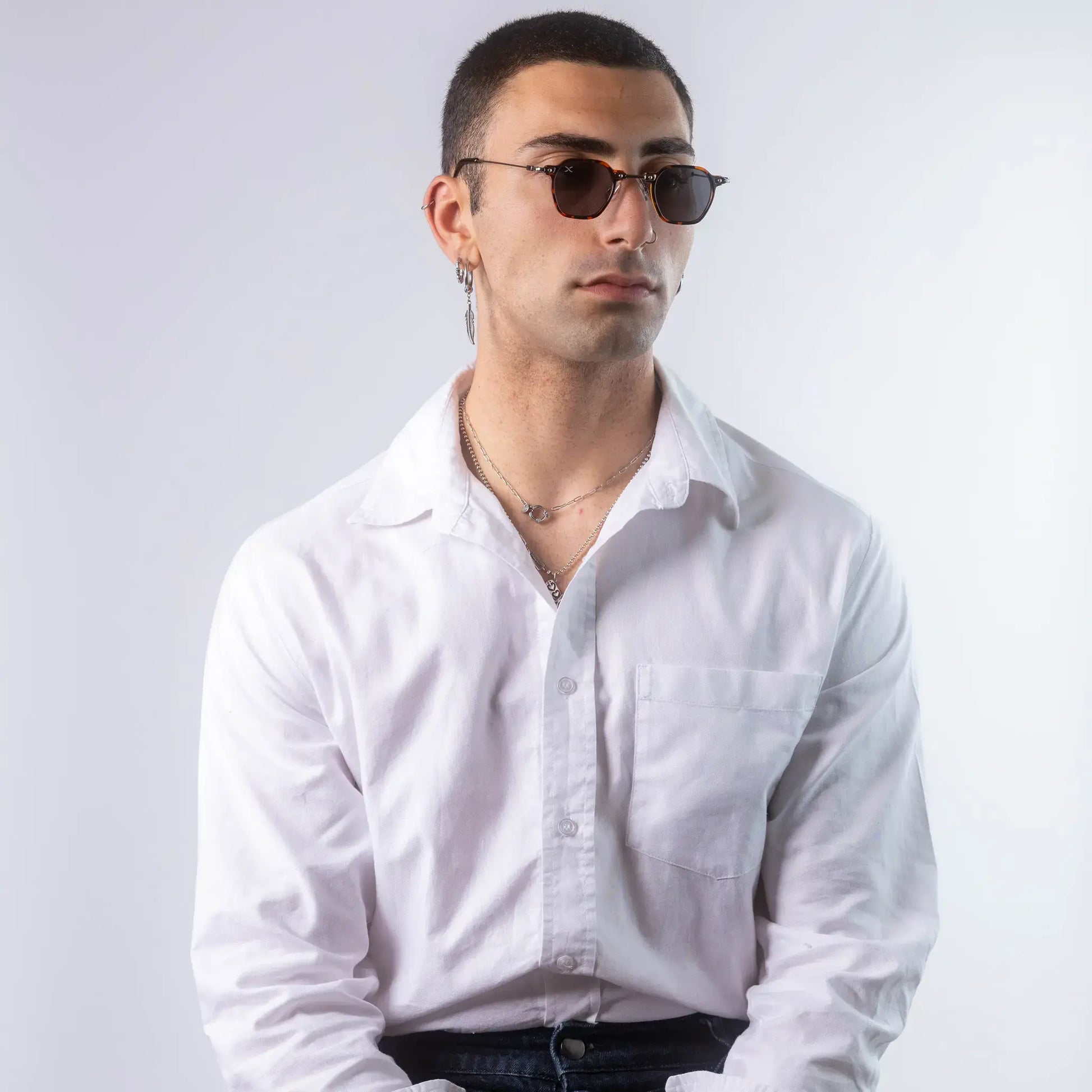 A male model wearing Exposure Sunglasses polarized sunglasses with brown frames and black lenses, posing against a white background.
