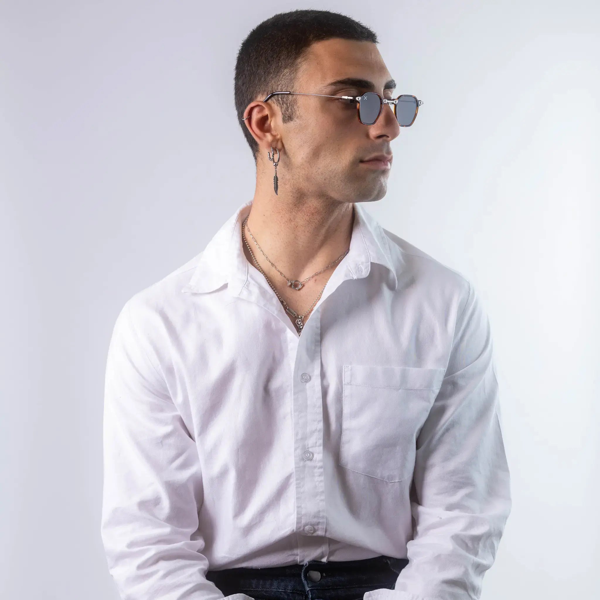 A male model wearing Exposure Sunglasses polarized sunglasses with brown frames and black lenses, posing against a white background.