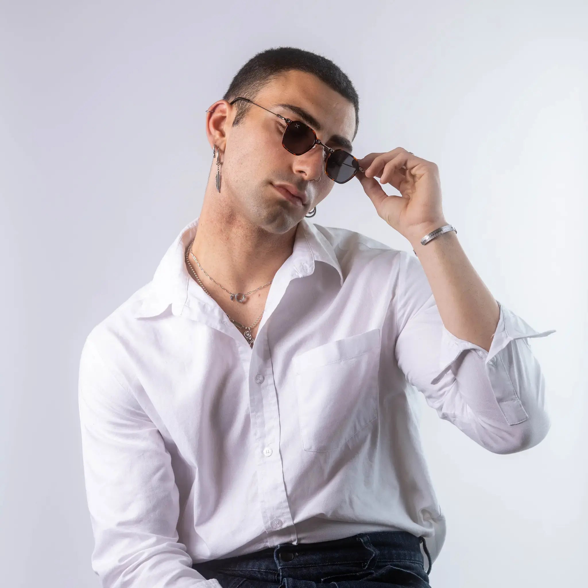 A male model wearing Exposure Sunglasses polarized sunglasses with brown frames and black lenses, posing against a white background.