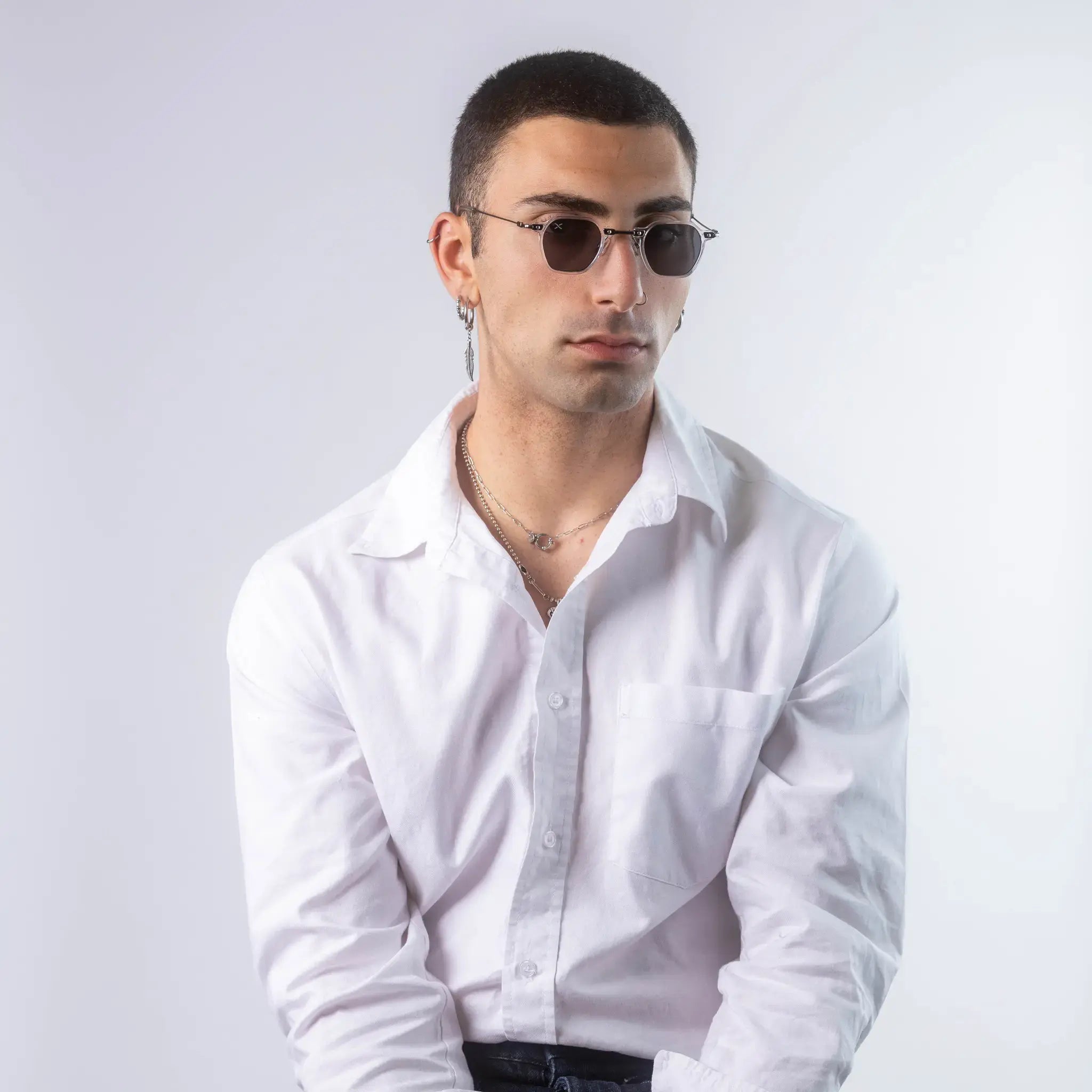 A male model wearing Exposure Sunglasses polarized sunglasses with white frames and black lenses, posing against a white background.