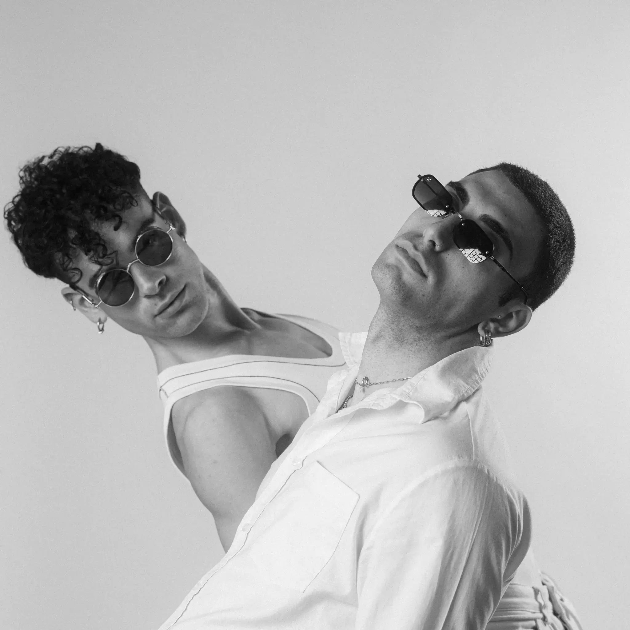 Two models wearing Exposure Sunglasses polarized sunglasses with black frames and tinted lenses, posing against a white background.