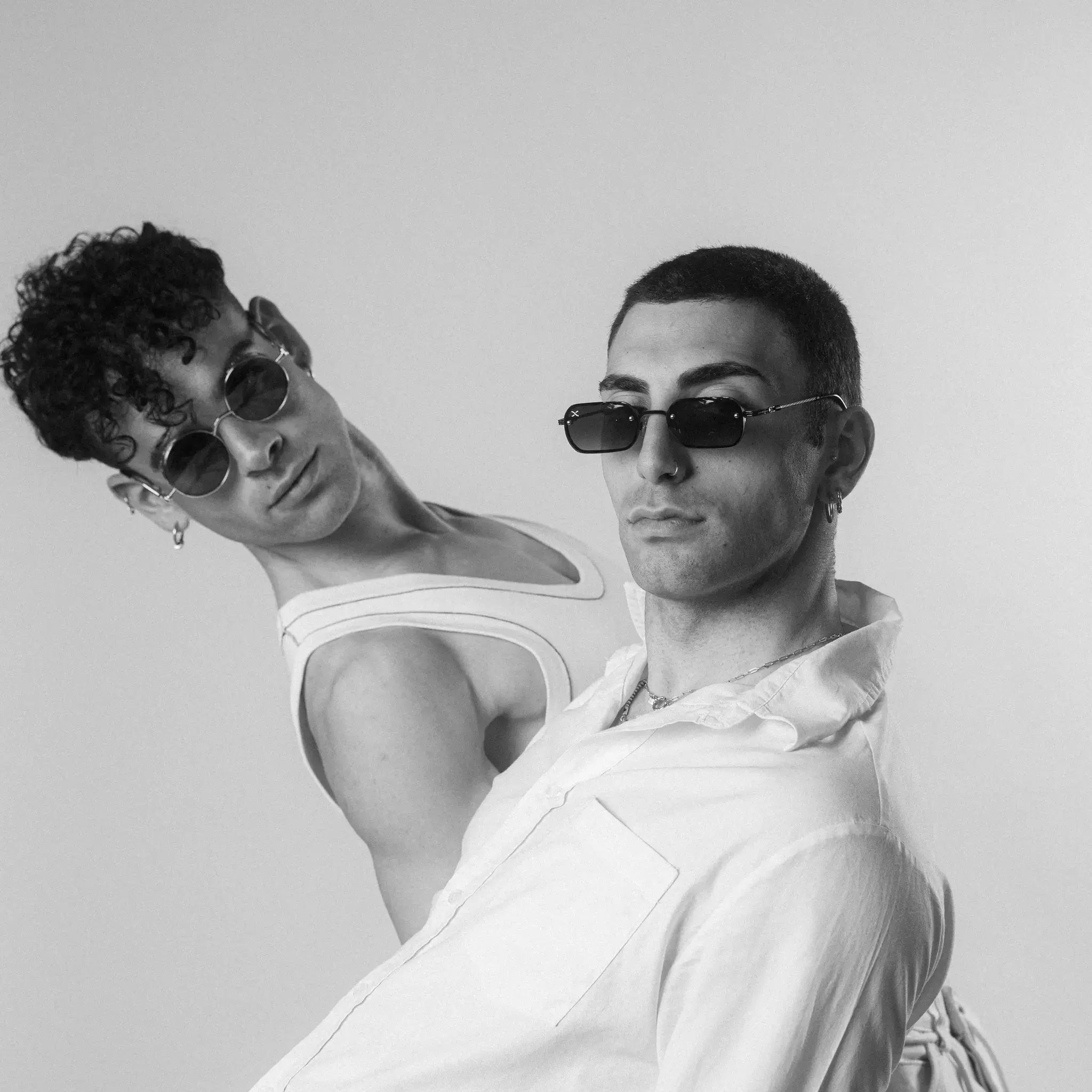 Two models wearing Exposure Sunglasses polarized sunglasses with black frames and tinted lenses, posing against a white background.