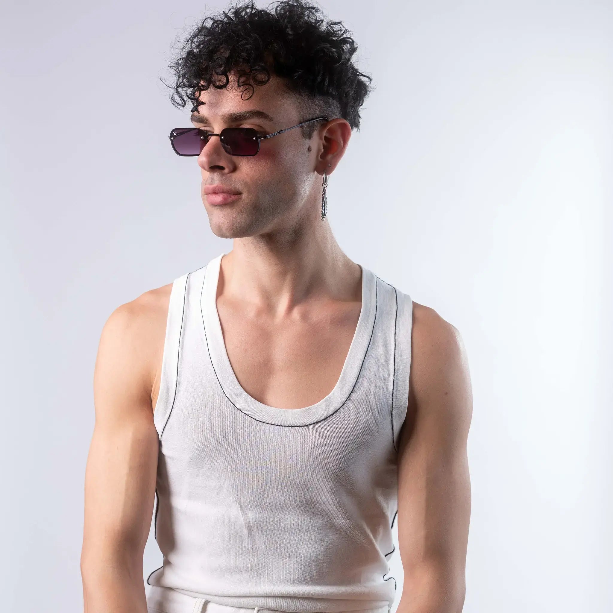 A male model wearing Exposure Sunglasses polarized sunglasses with black frames and purple lenses, posing against a white background.