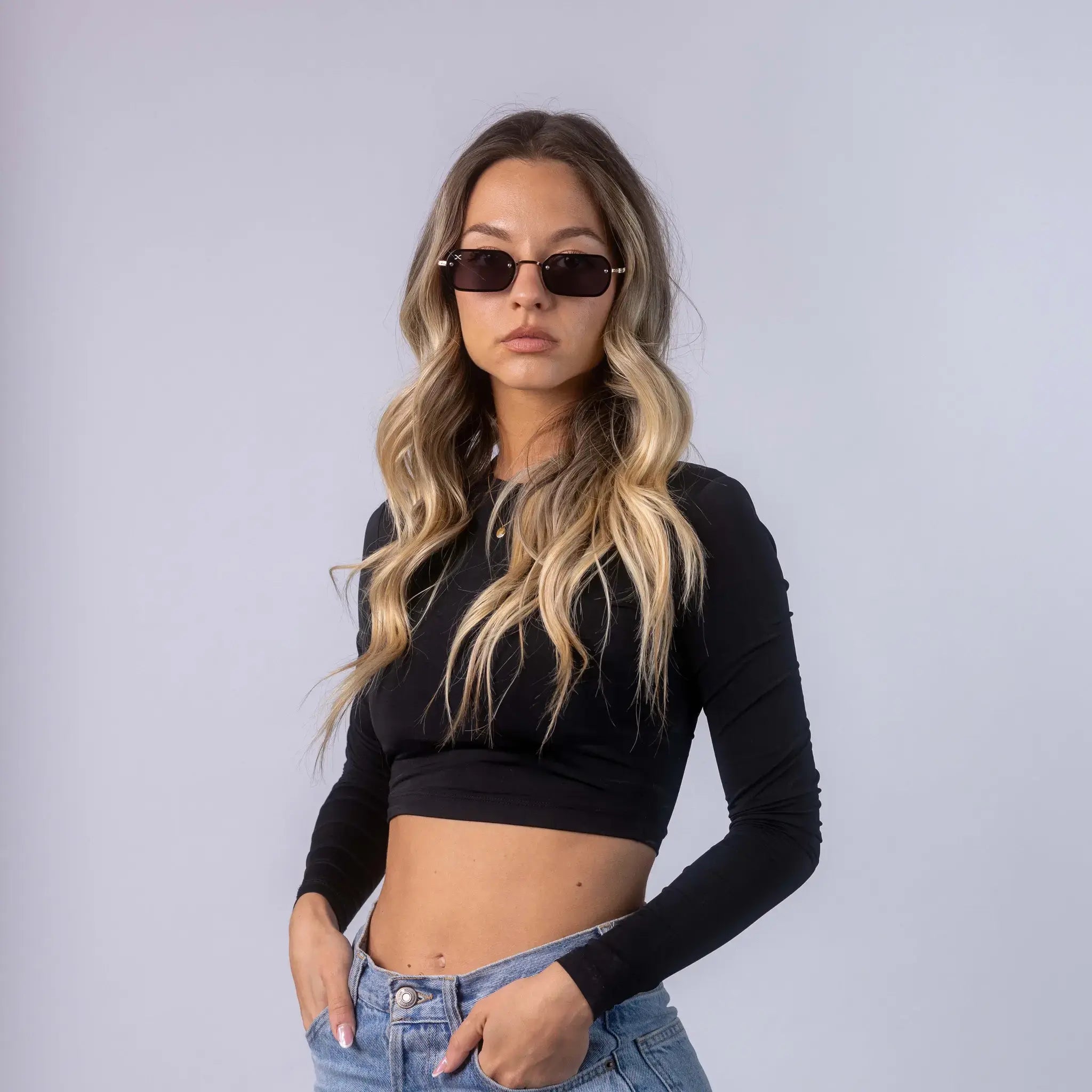 A female model wearing Exposure Sunglasses polarized sunglasses with gold frames and black lenses, posing against a white background.