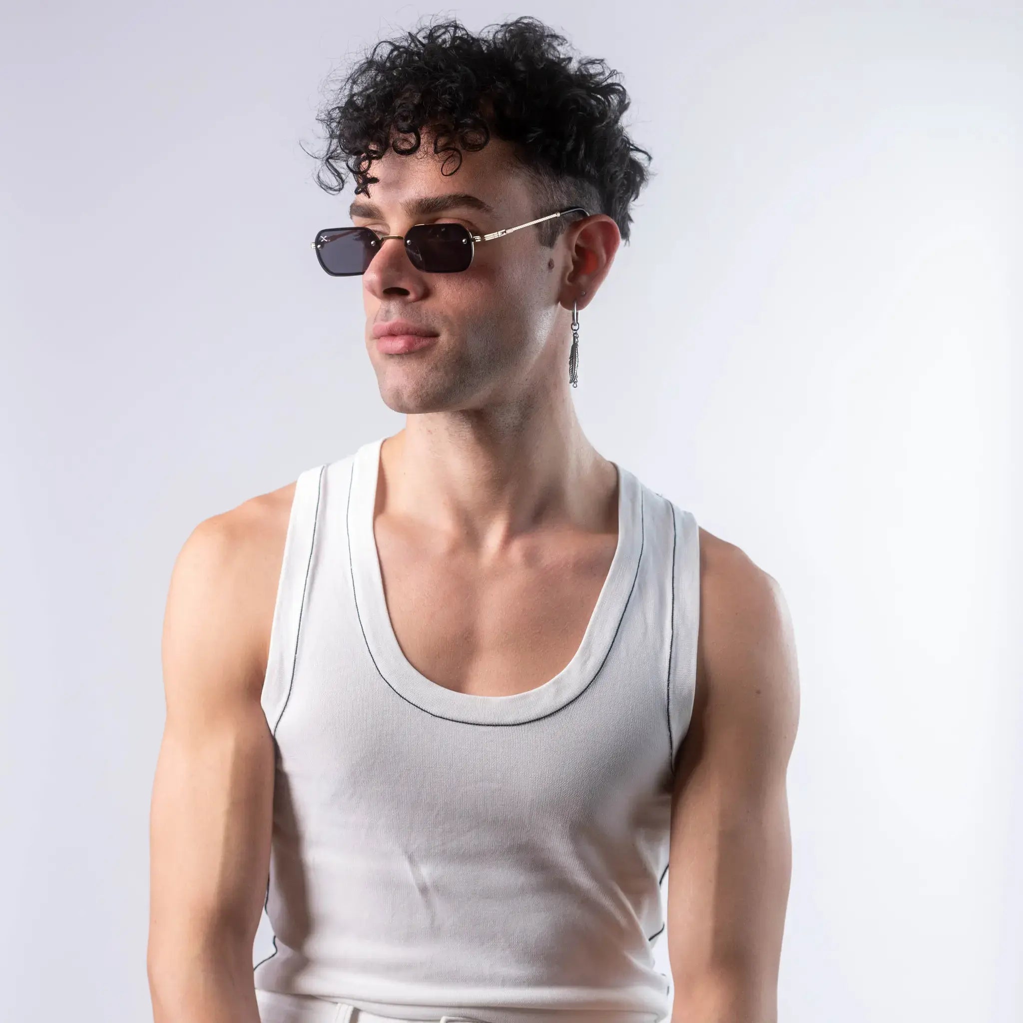 A male model wearing Exposure Sunglasses polarized sunglasses with gold frames and black lenses, posing against a white background.