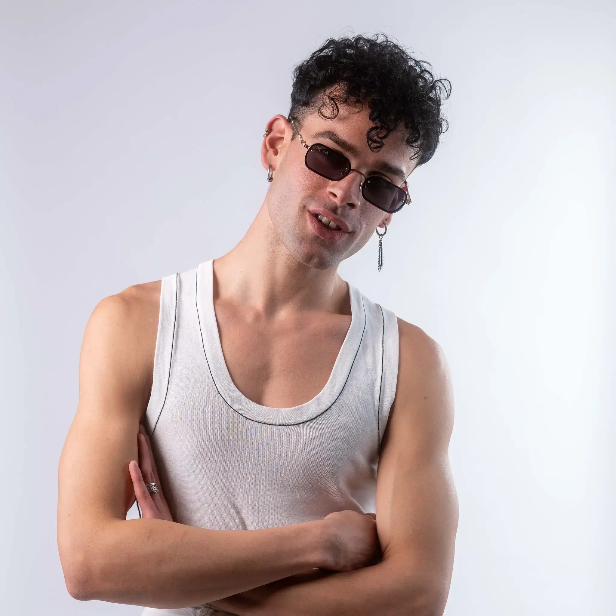 A male model wearing Exposure Sunglasses polarized sunglasses with gold frames and black lenses, posing against a white background.