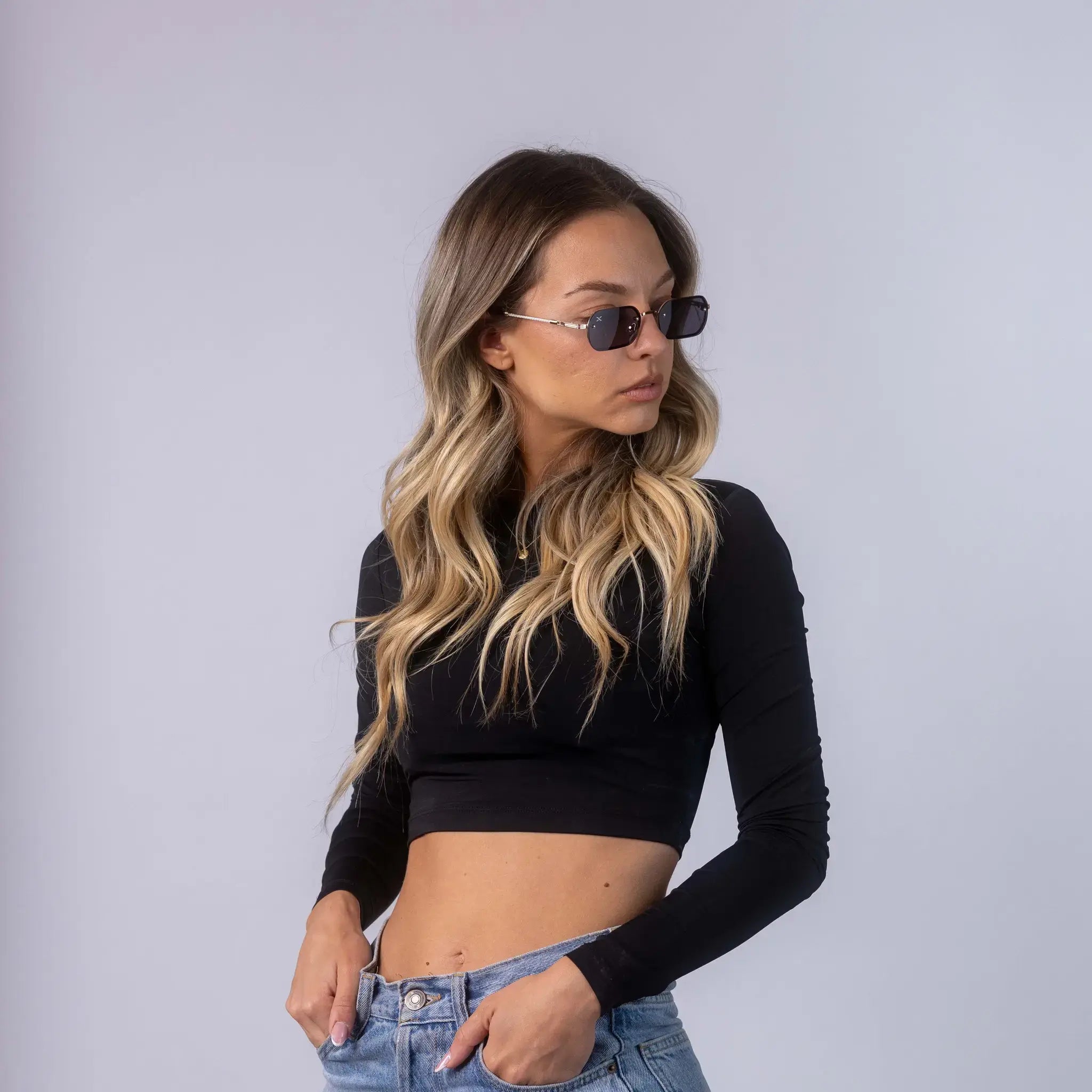 A female model wearing Exposure Sunglasses polarized sunglasses with gold frames and black lenses, posing against a white background.