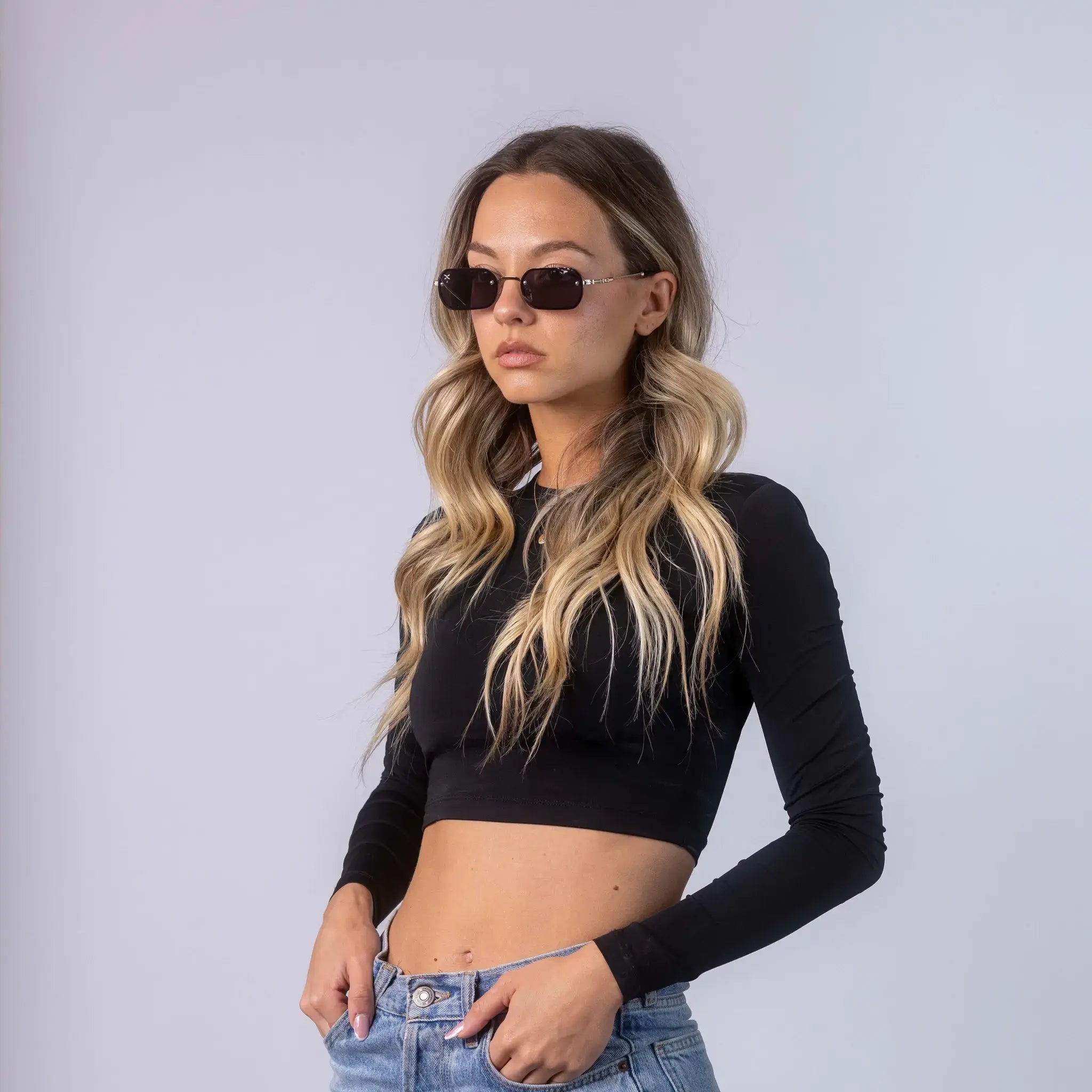 A female model wearing Exposure Sunglasses polarized sunglasses with gold frames and black lenses, posing against a white background.