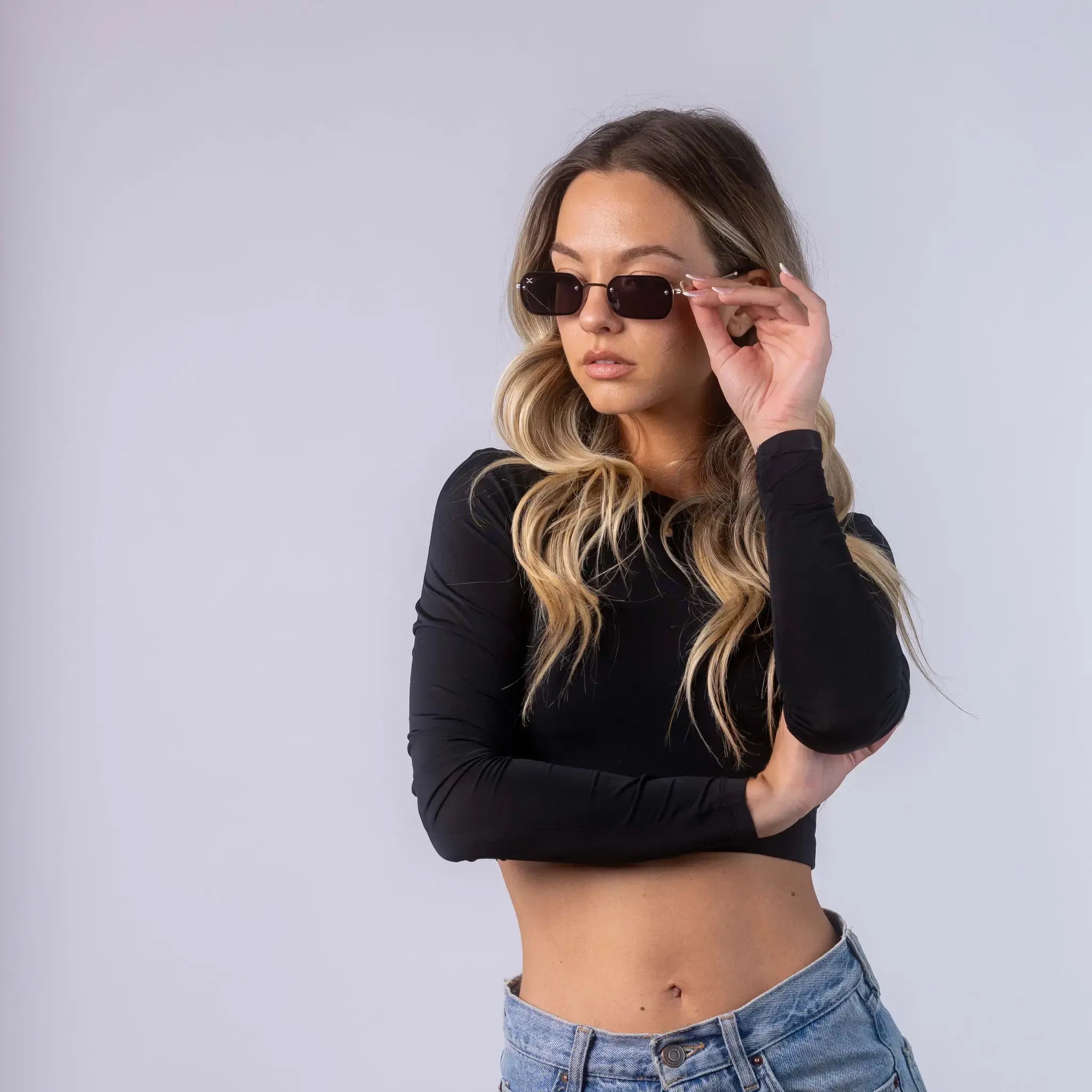 A female model wearing Exposure Sunglasses polarized sunglasses with gold frames and black lenses, posing against a white background.