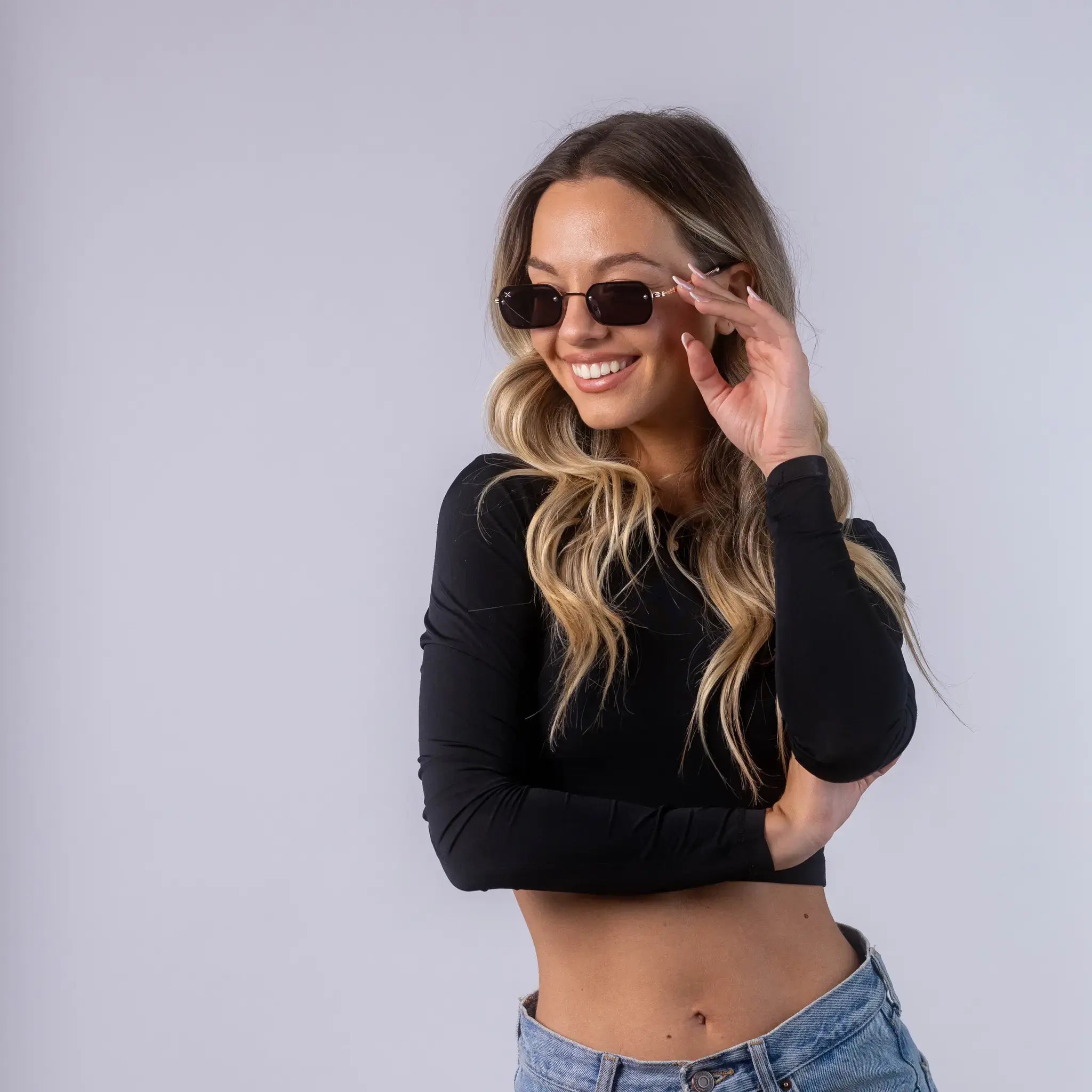 A female model wearing Exposure Sunglasses polarized sunglasses with gold frames and black lenses, posing against a white background.