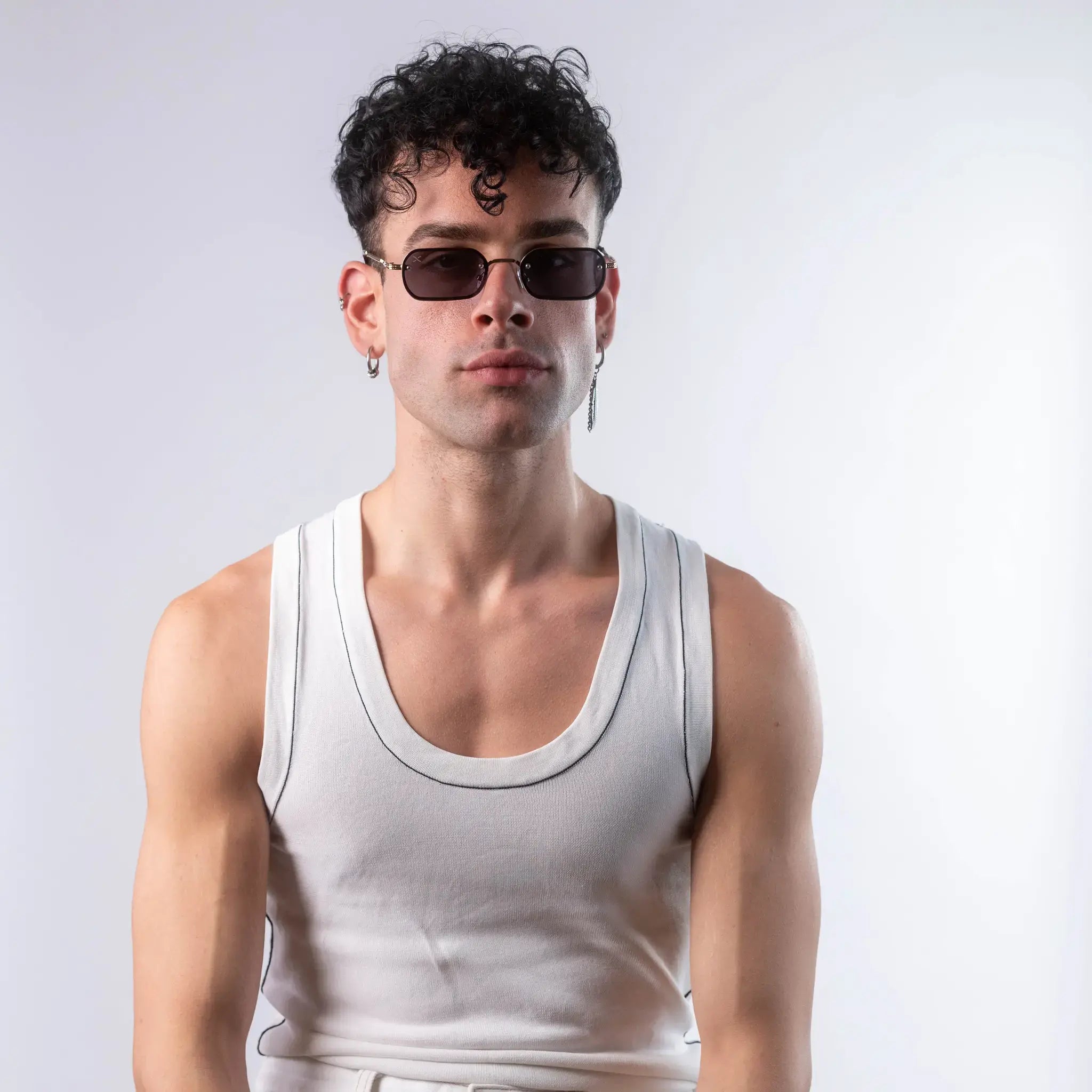 A male model wearing Exposure Sunglasses polarized sunglasses with gold frames and black lenses, posing against a white background.