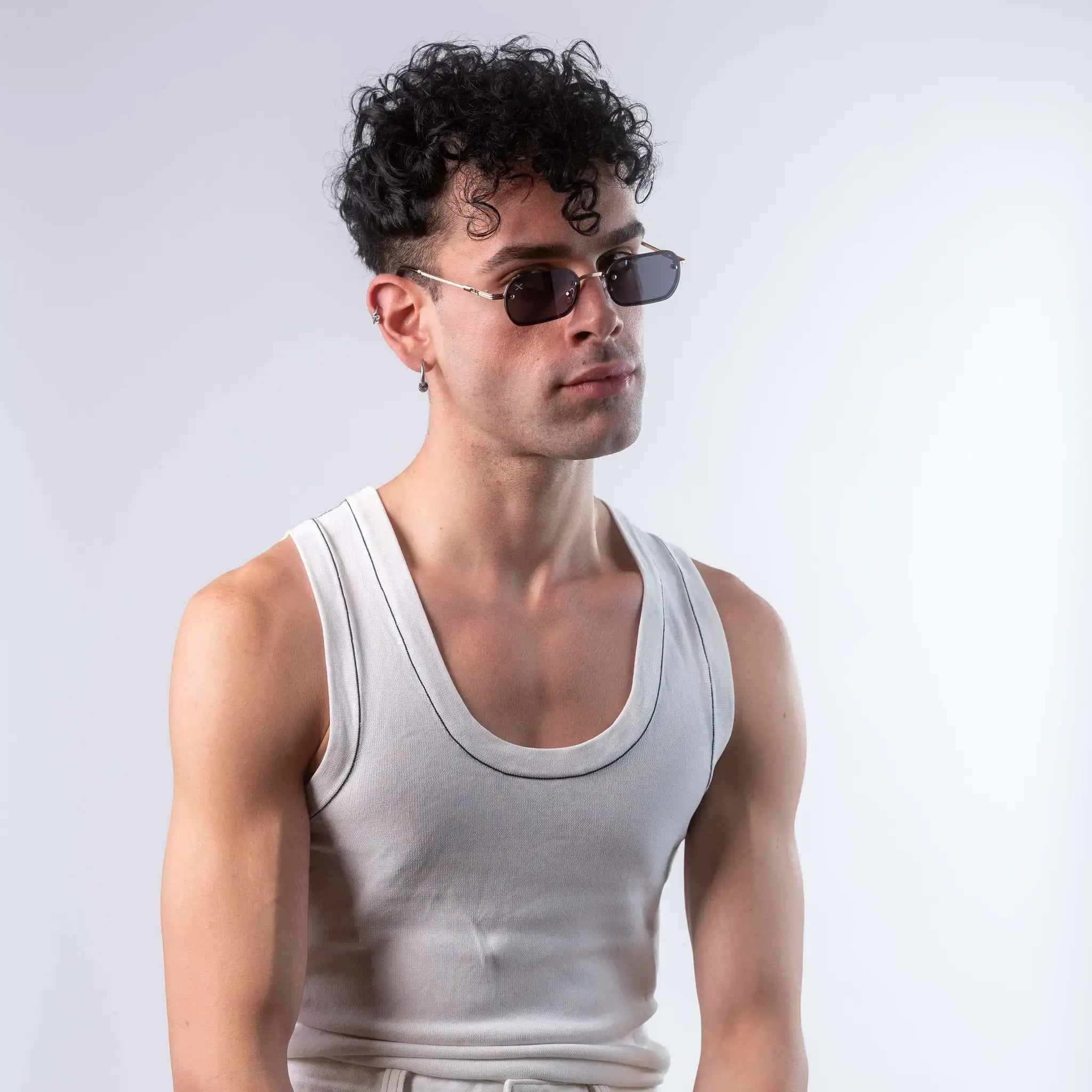 A male model wearing Exposure Sunglasses polarized sunglasses with gold frames and black lenses, posing against a white background.