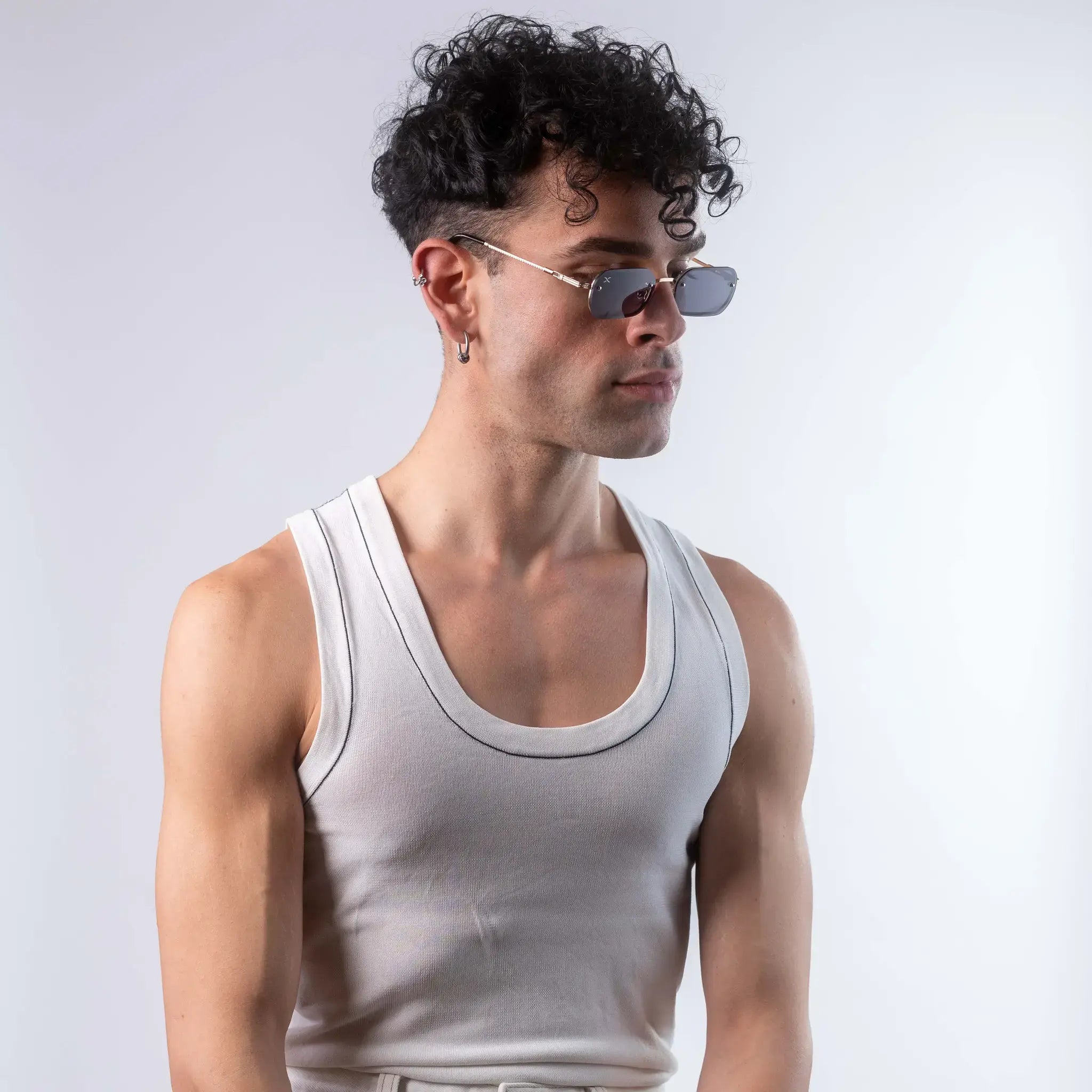 A male model wearing Exposure Sunglasses polarized sunglasses with gold frames and black lenses, posing against a white background.