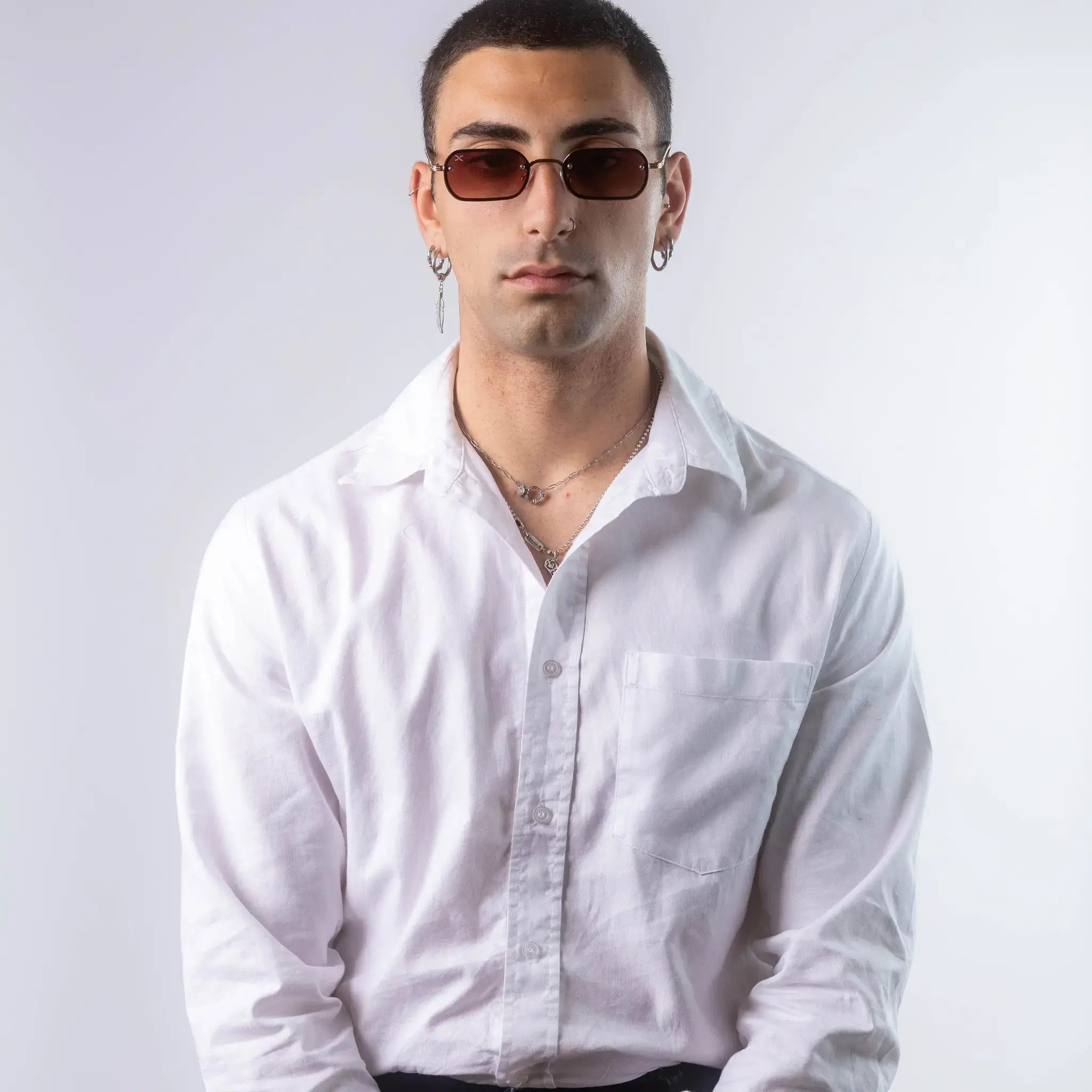 A male model wearing Exposure Sunglasses polarized sunglasses with gold frames and brown lenses, posing against a white background.