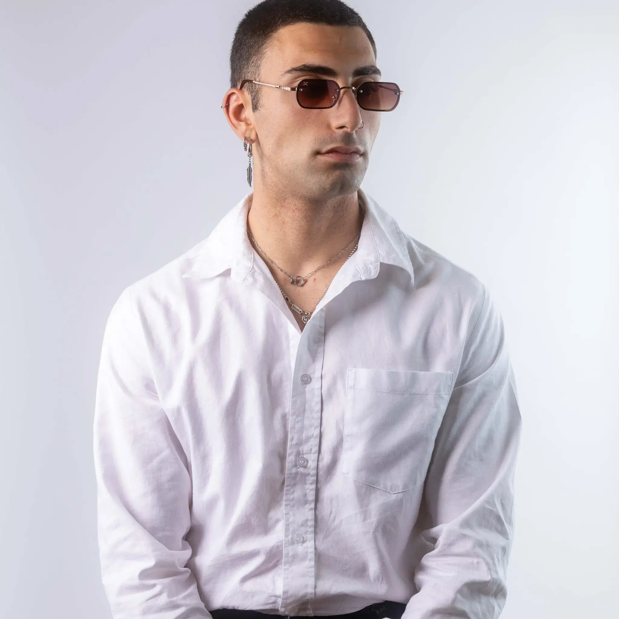 A male model wearing Exposure Sunglasses polarized sunglasses with gold frames and brown lenses, posing against a white background.