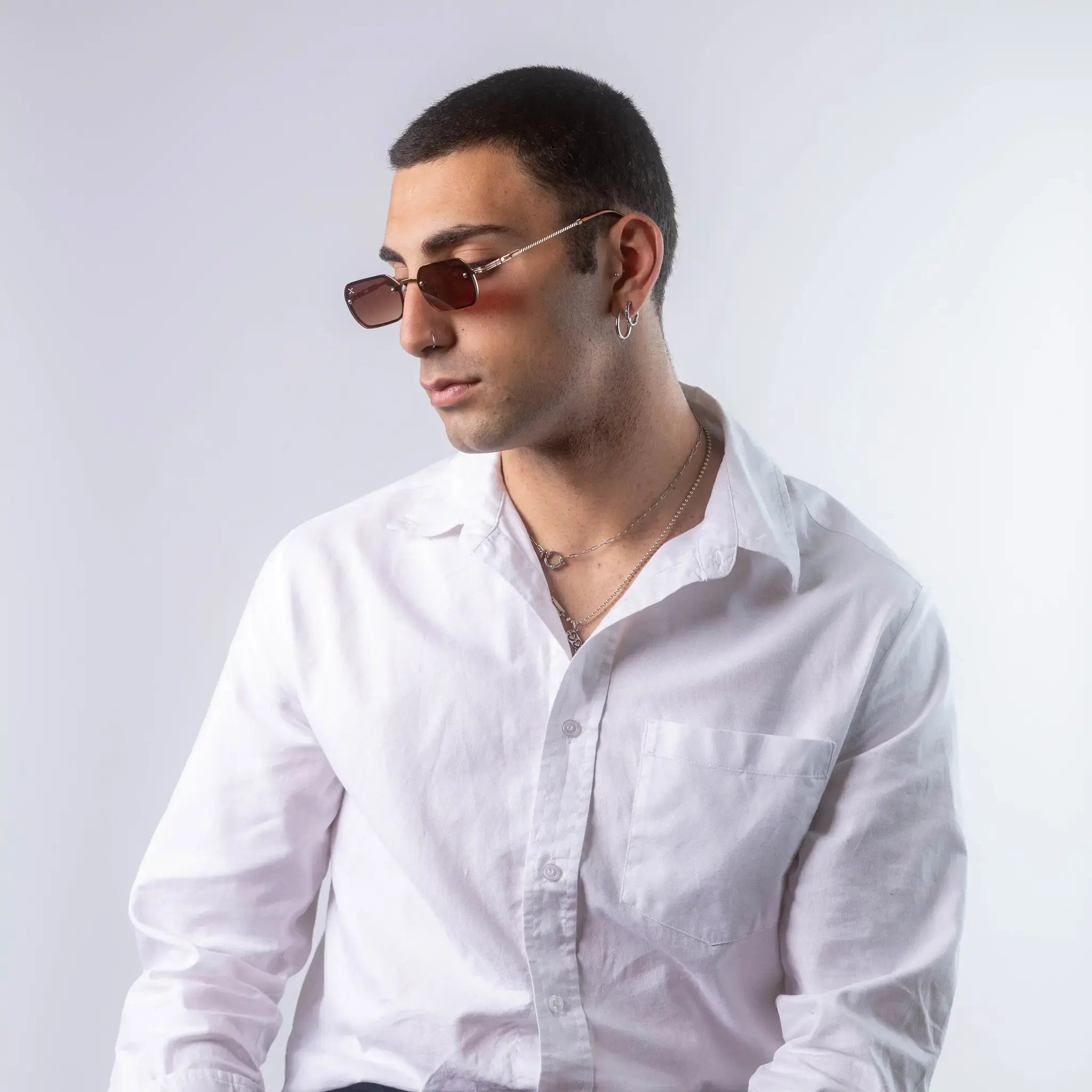 A male model wearing Exposure Sunglasses polarized sunglasses with gold frames and brown lenses, posing against a white background.