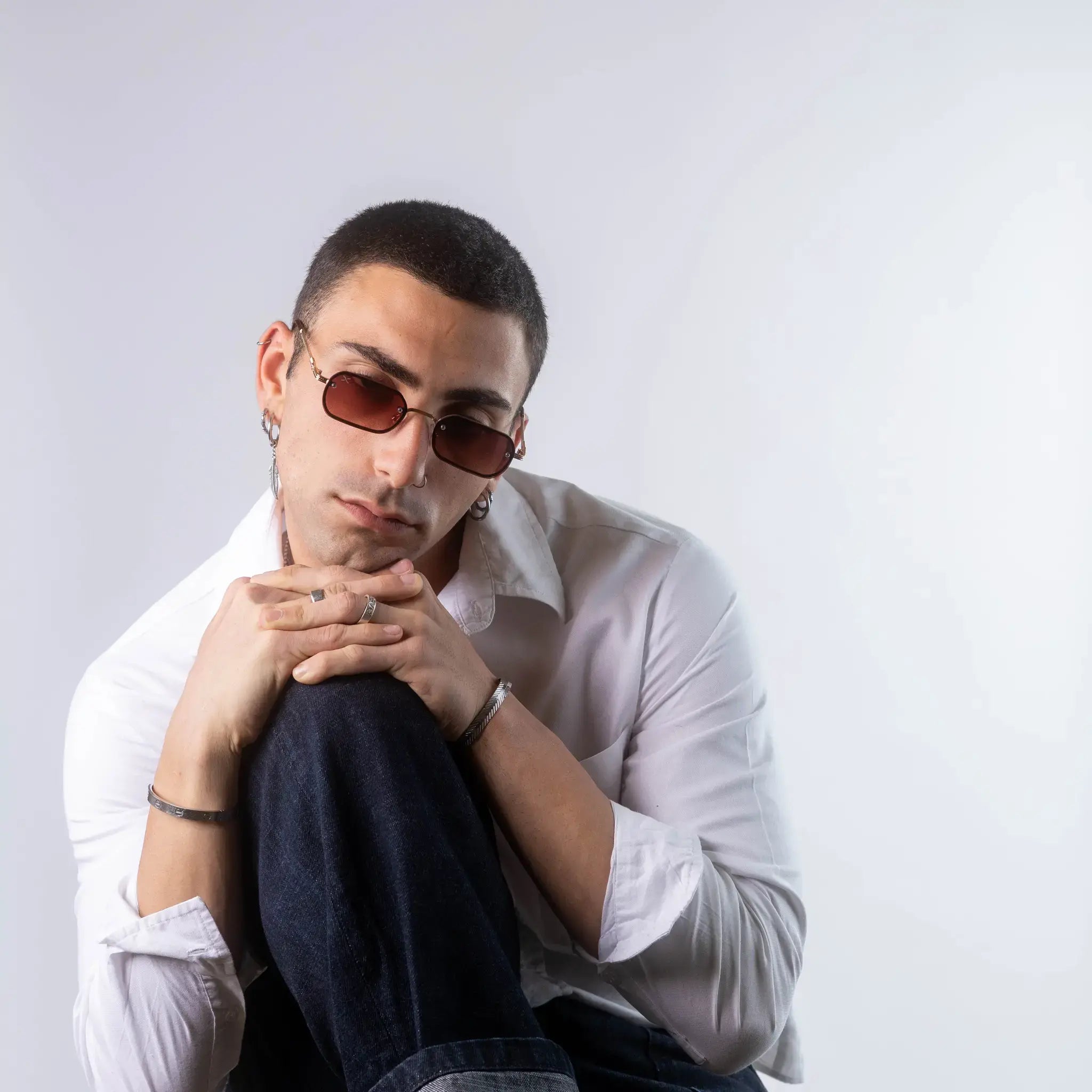 A male model wearing Exposure Sunglasses polarized sunglasses with gold frames and brown lenses, posing against a white background.