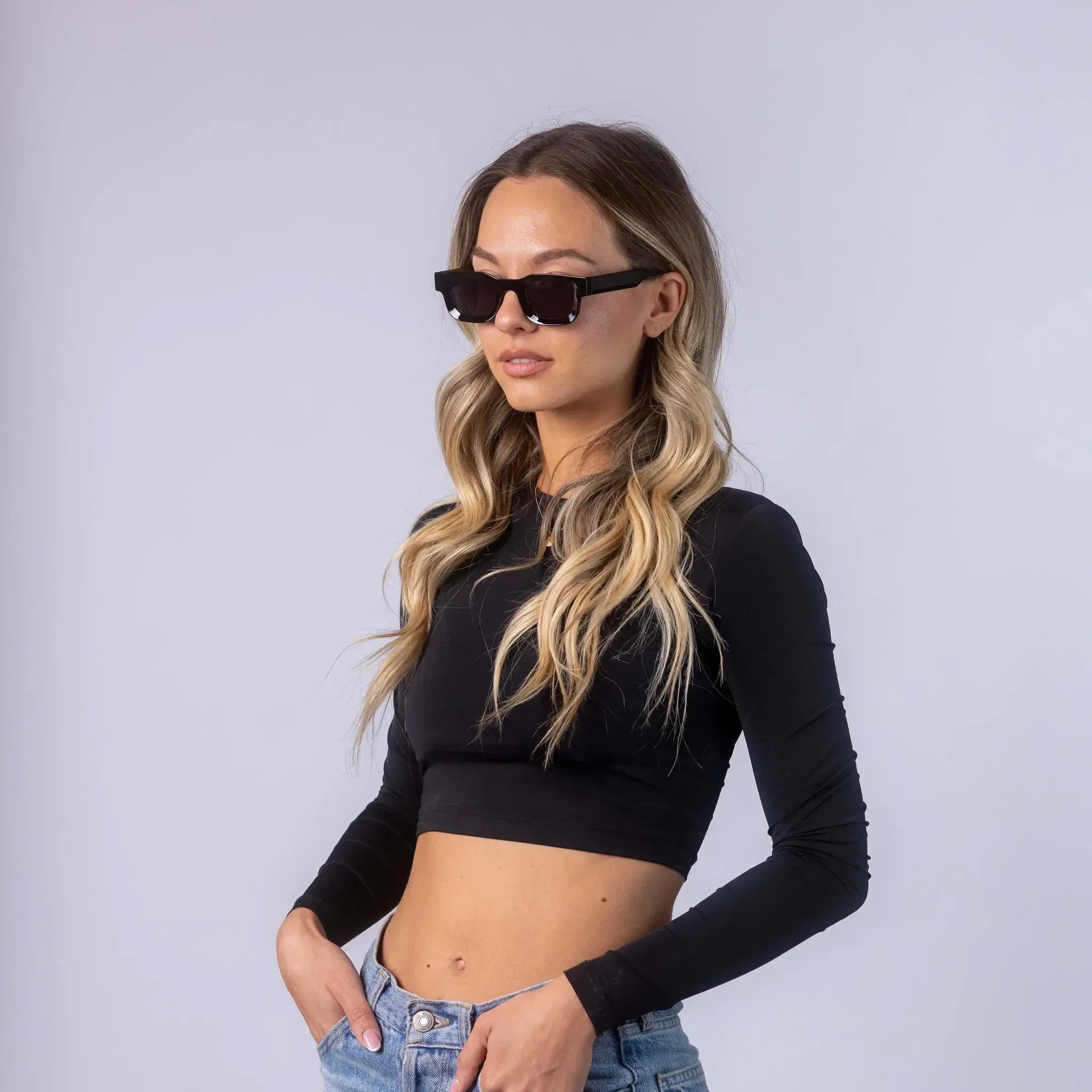 A female model wearing Exposure Sunglasses polarized sunglasses with black frames and black lenses, posing against a white background.