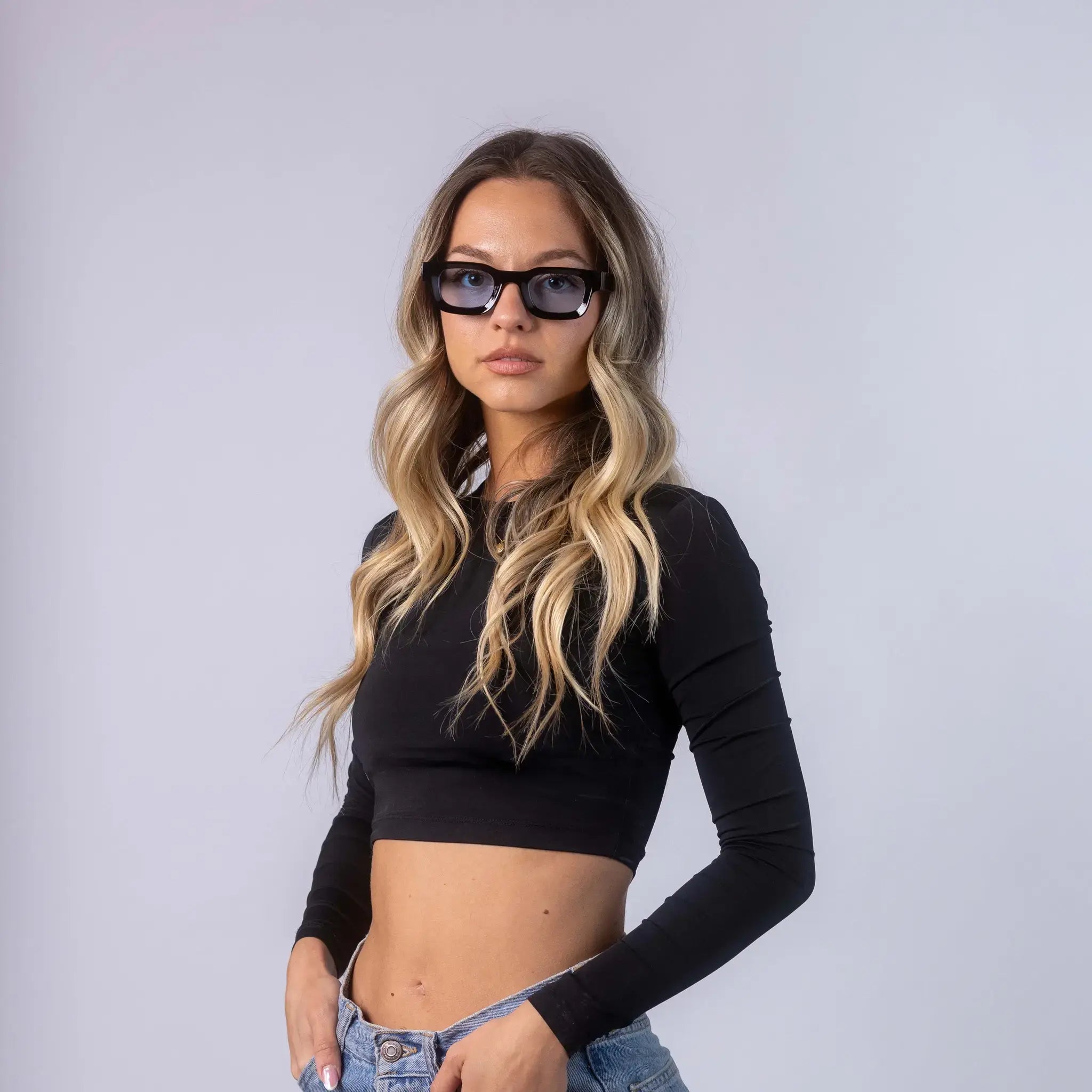 A female model wearing Exposure Sunglasses polarized sunglasses with black frames and blue lenses, posing against a white background.