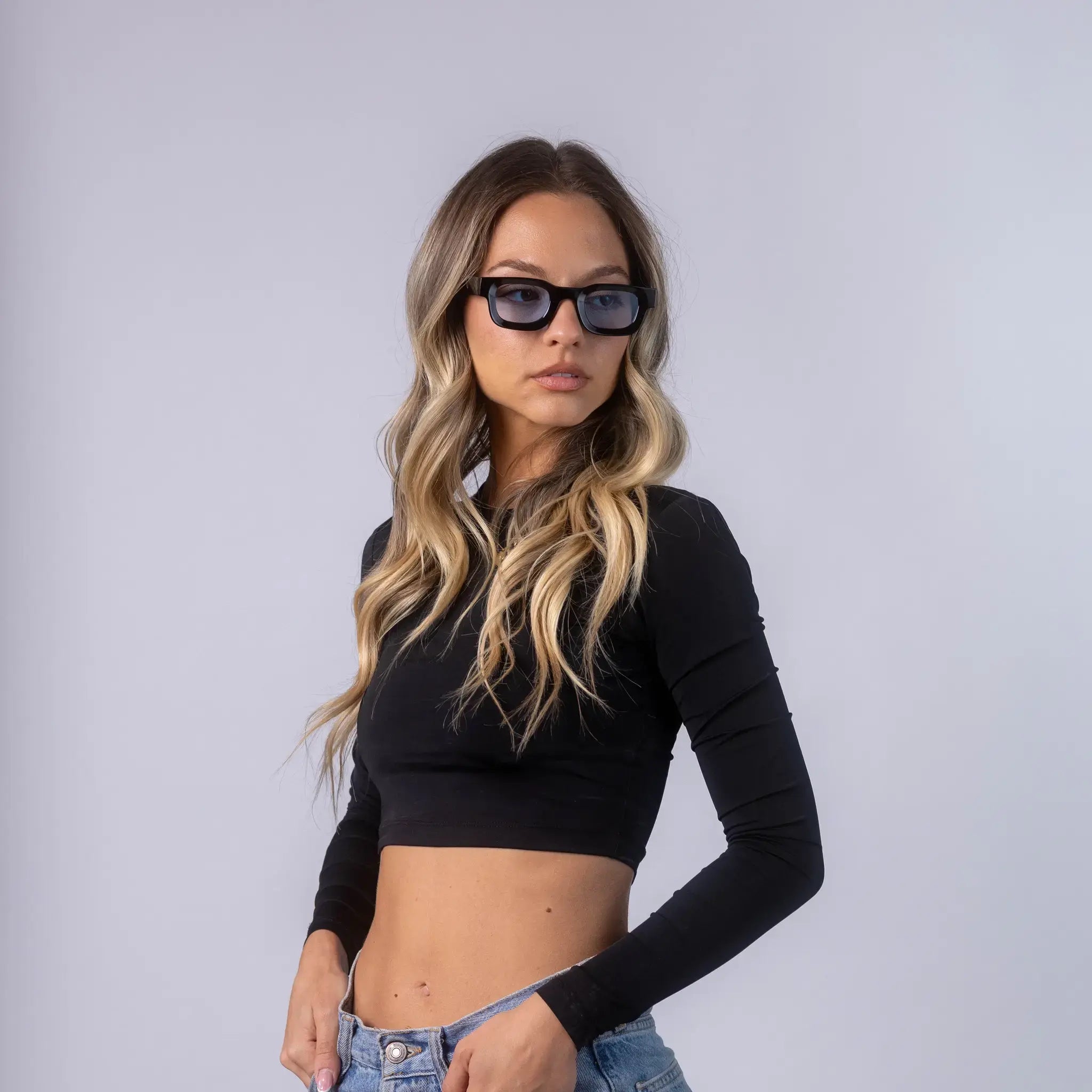 A female model wearing Exposure Sunglasses polarized sunglasses with black frames and blue lenses, posing against a white background.