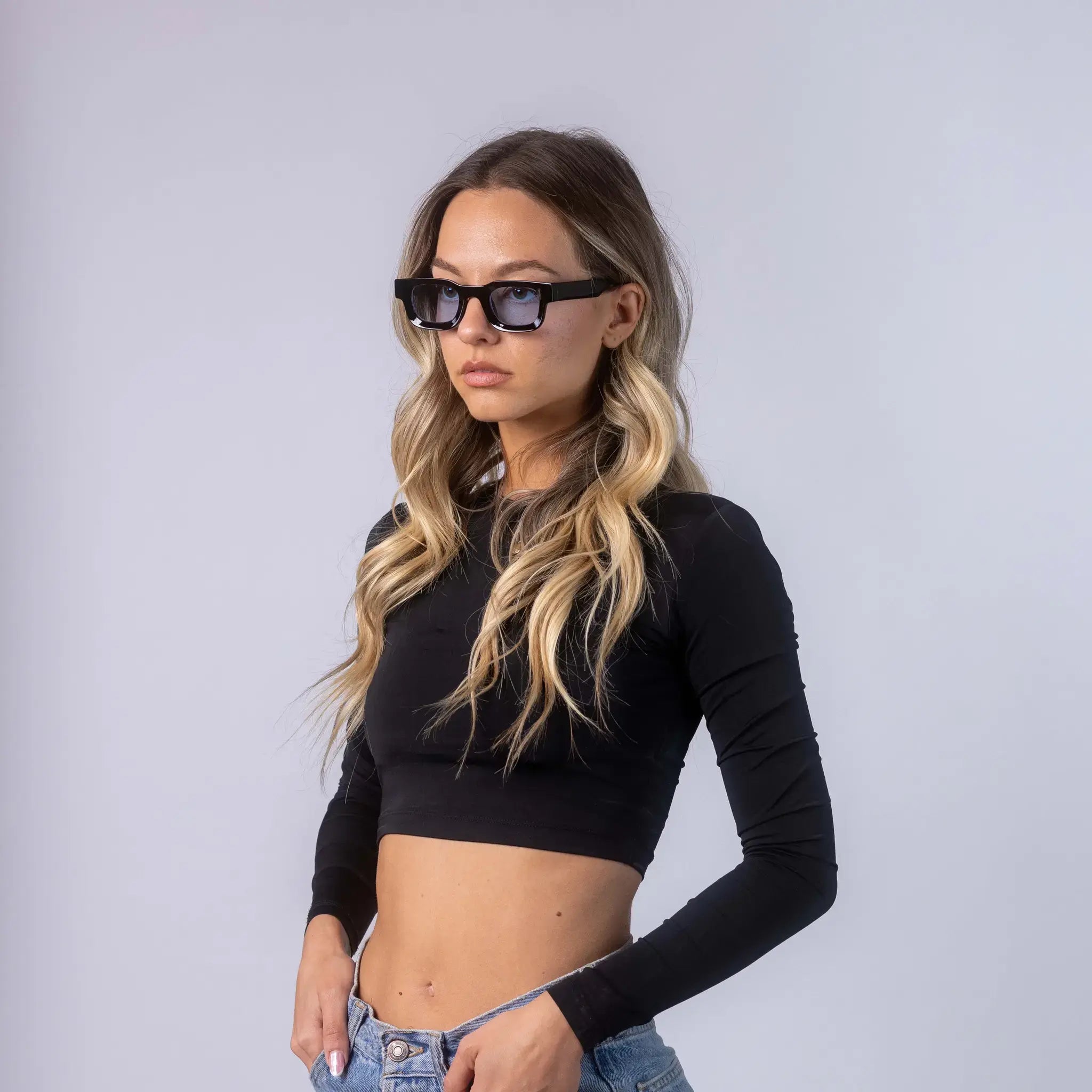 A female model wearing Exposure Sunglasses polarized sunglasses with black frames and blue lenses, posing against a white background.