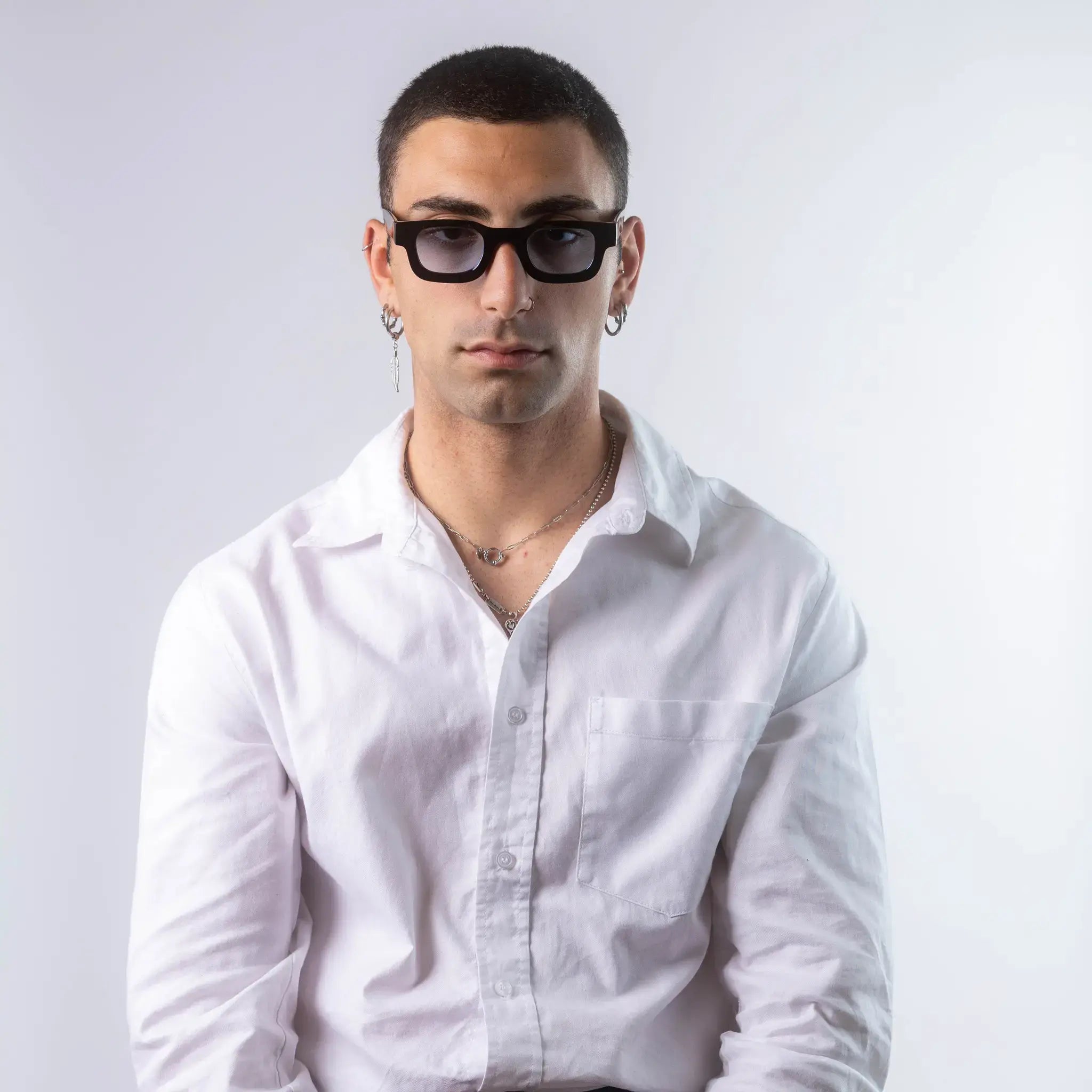 A male model wearing Exposure Sunglasses polarized sunglasses with black frames and blue lenses, posing against a white background.