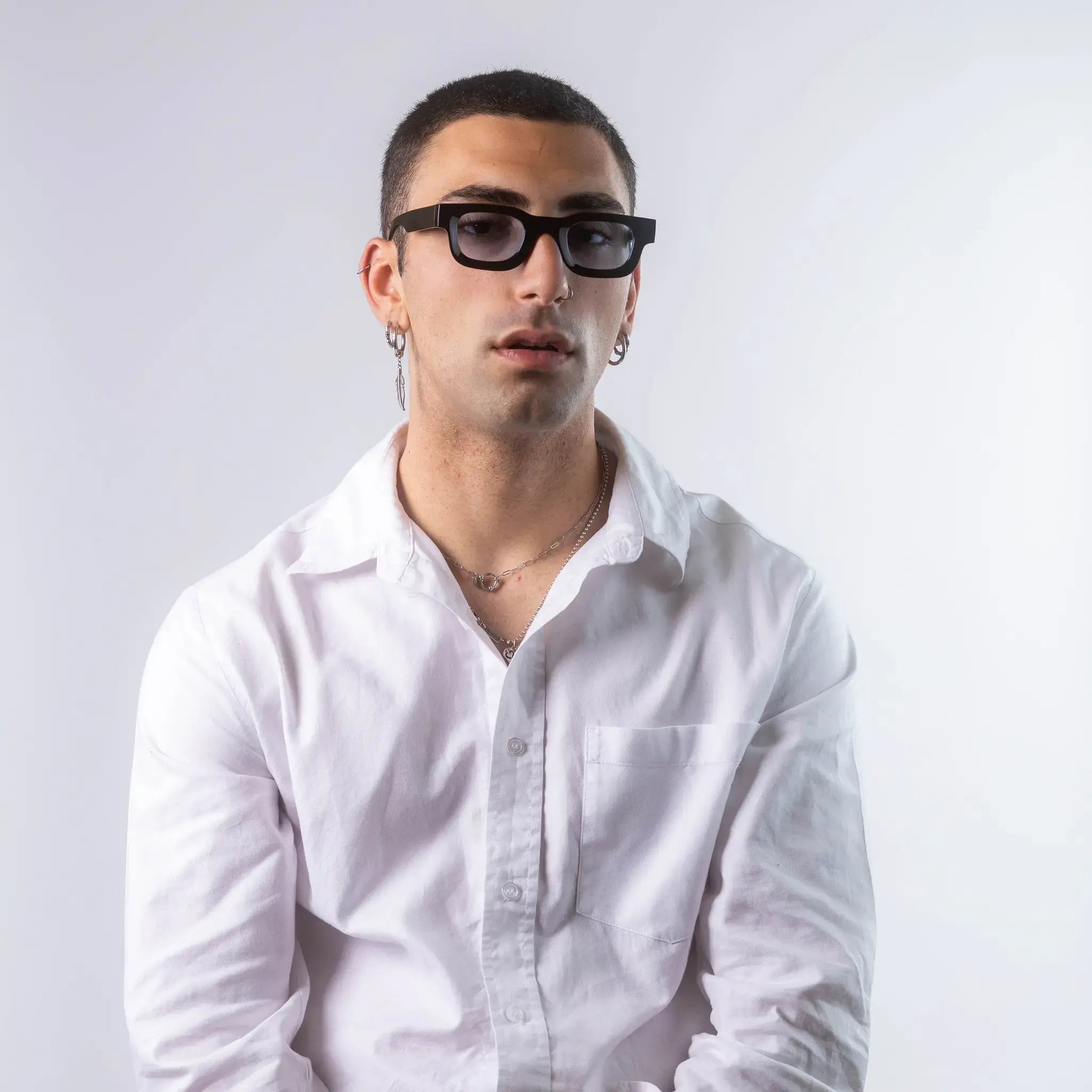 A male model wearing Exposure Sunglasses polarized sunglasses with black frames and blue lenses, posing against a white background.