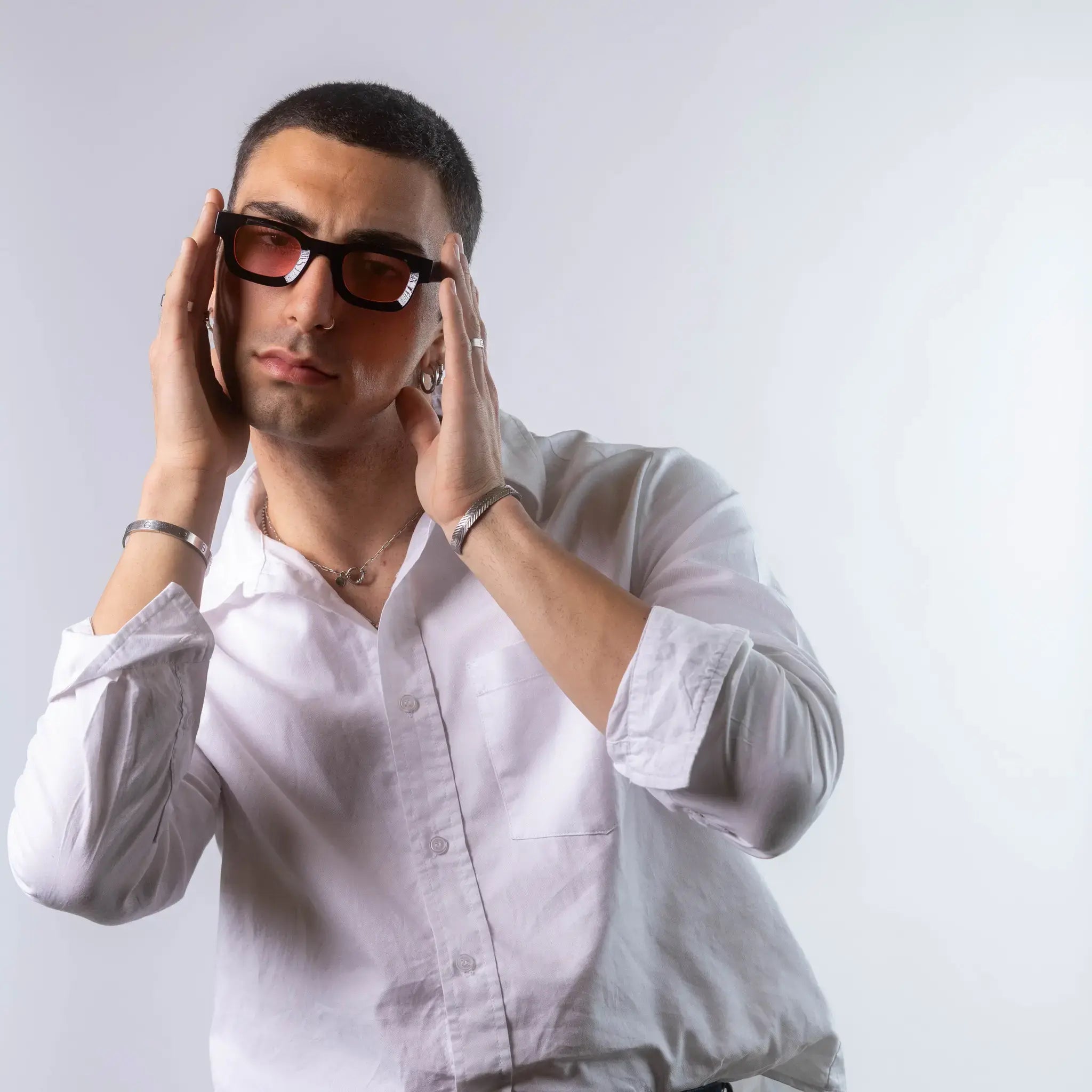 A male model wearing Exposure Sunglasses polarized sunglasses with black frames and pink lenses, posing against a white background.