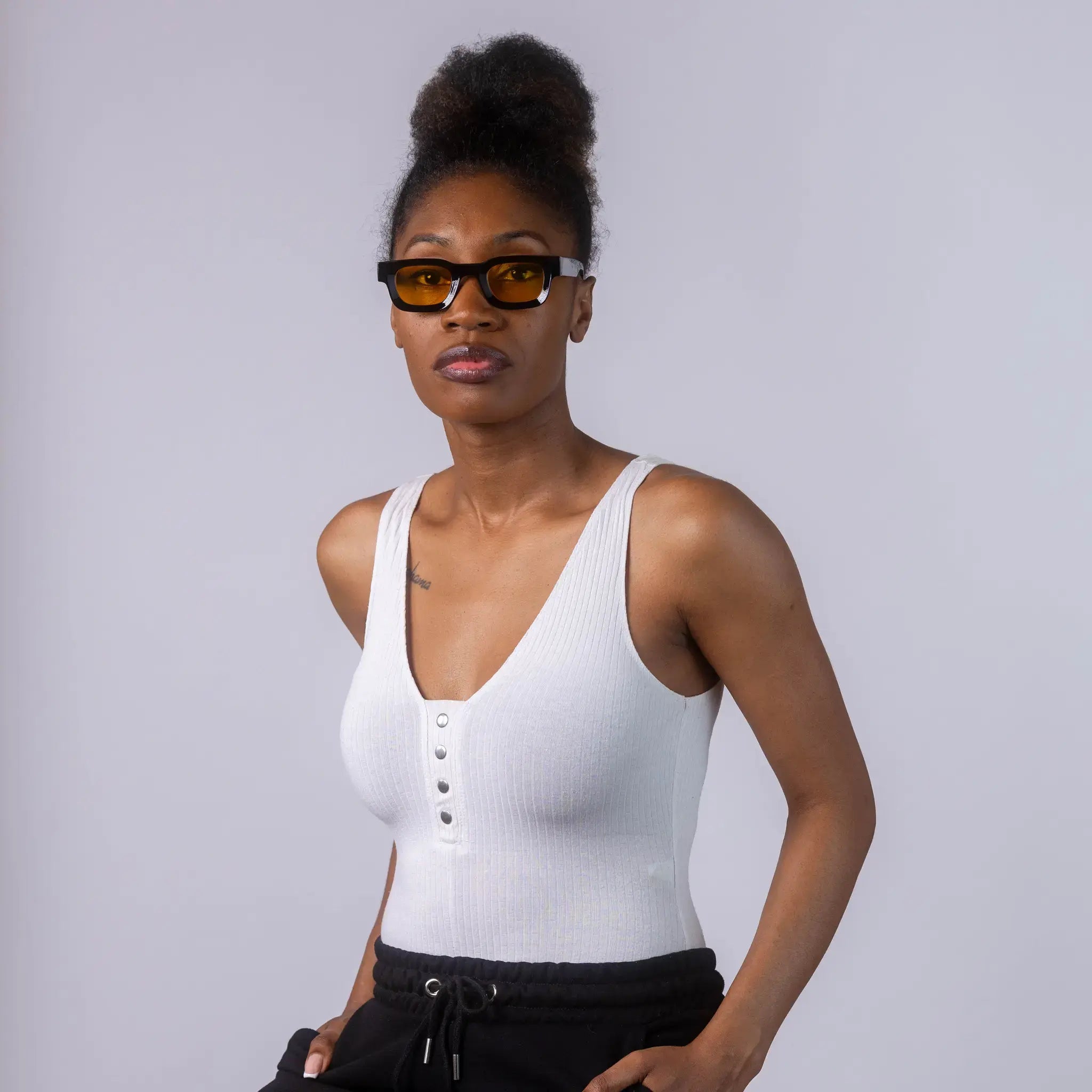 A female model wearing Exposure Sunglasses polarized sunglasses with black frames and yellow lenses, posing against a white background.