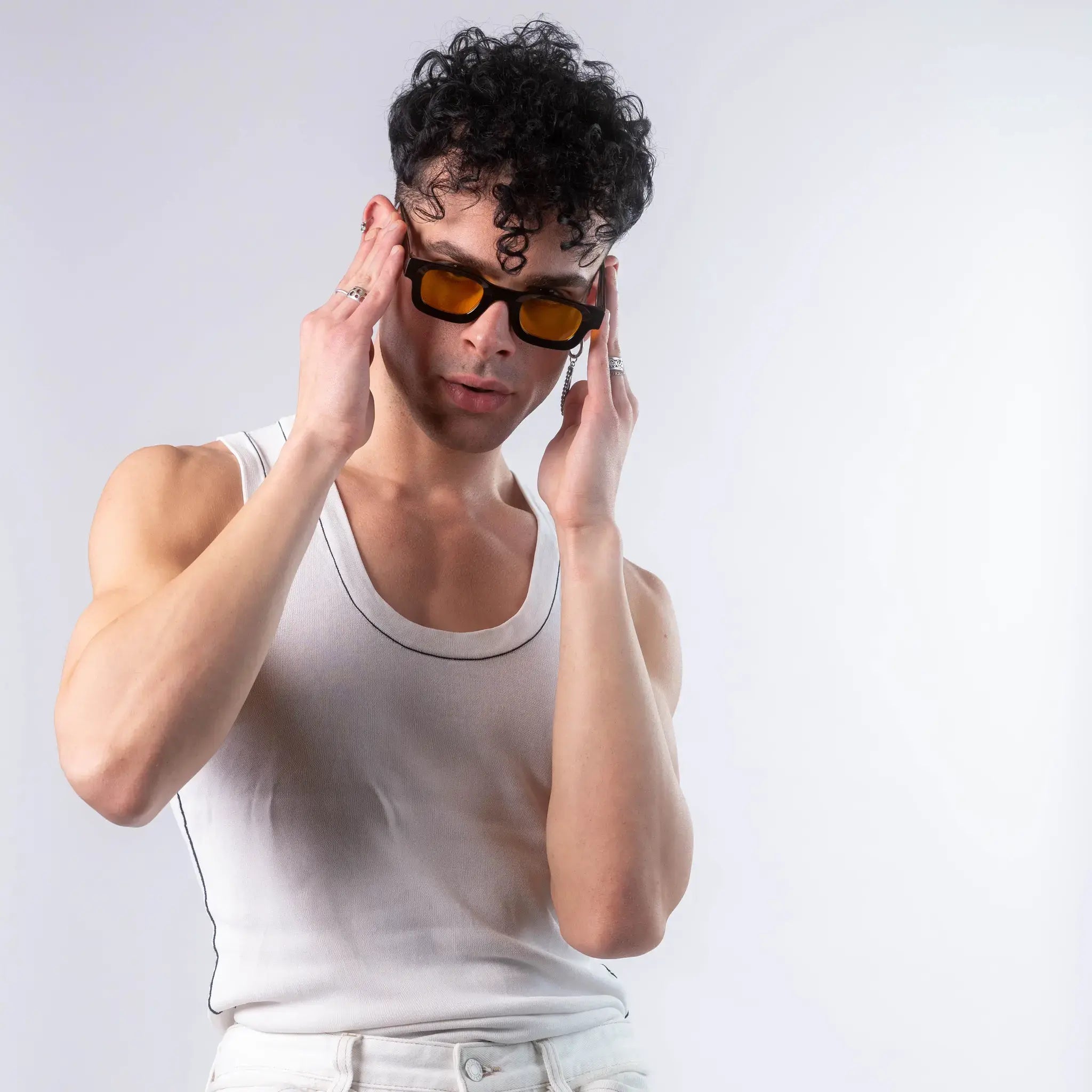 A male model wearing Exposure Sunglasses polarized sunglasses with black frames and yellow lenses, posing against a white background.