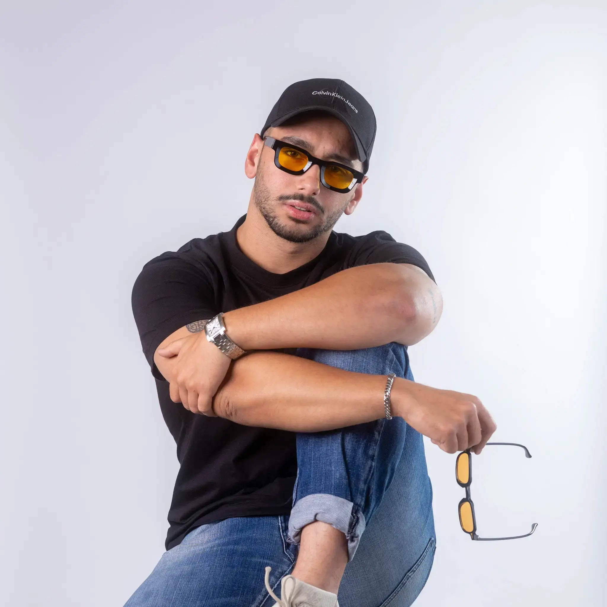 A male model wearing Exposure Sunglasses polarized sunglasses with black frames and yellow lenses, posing against a white background.