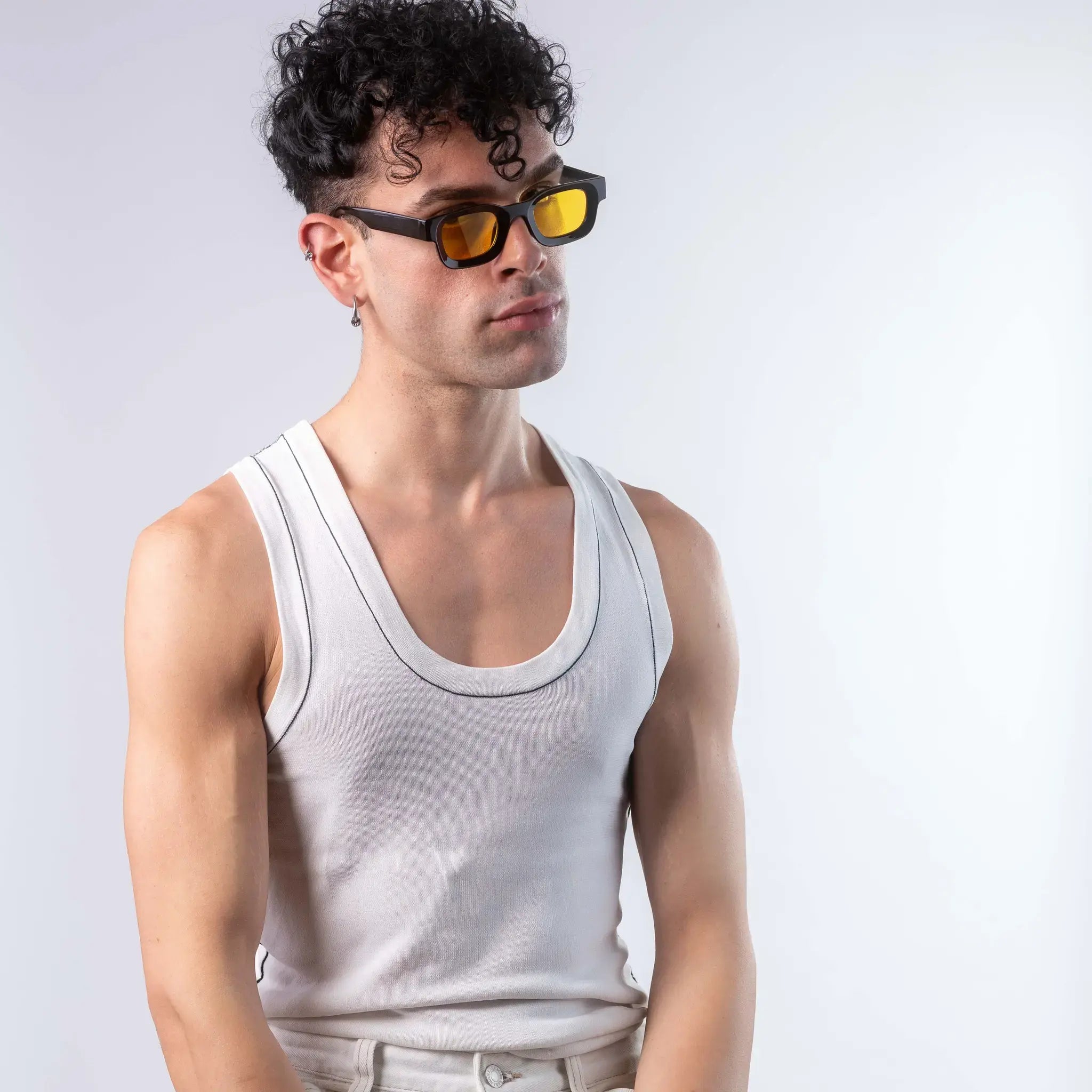 A male model wearing Exposure Sunglasses polarized sunglasses with black frames and yellow lenses, posing against a white background.