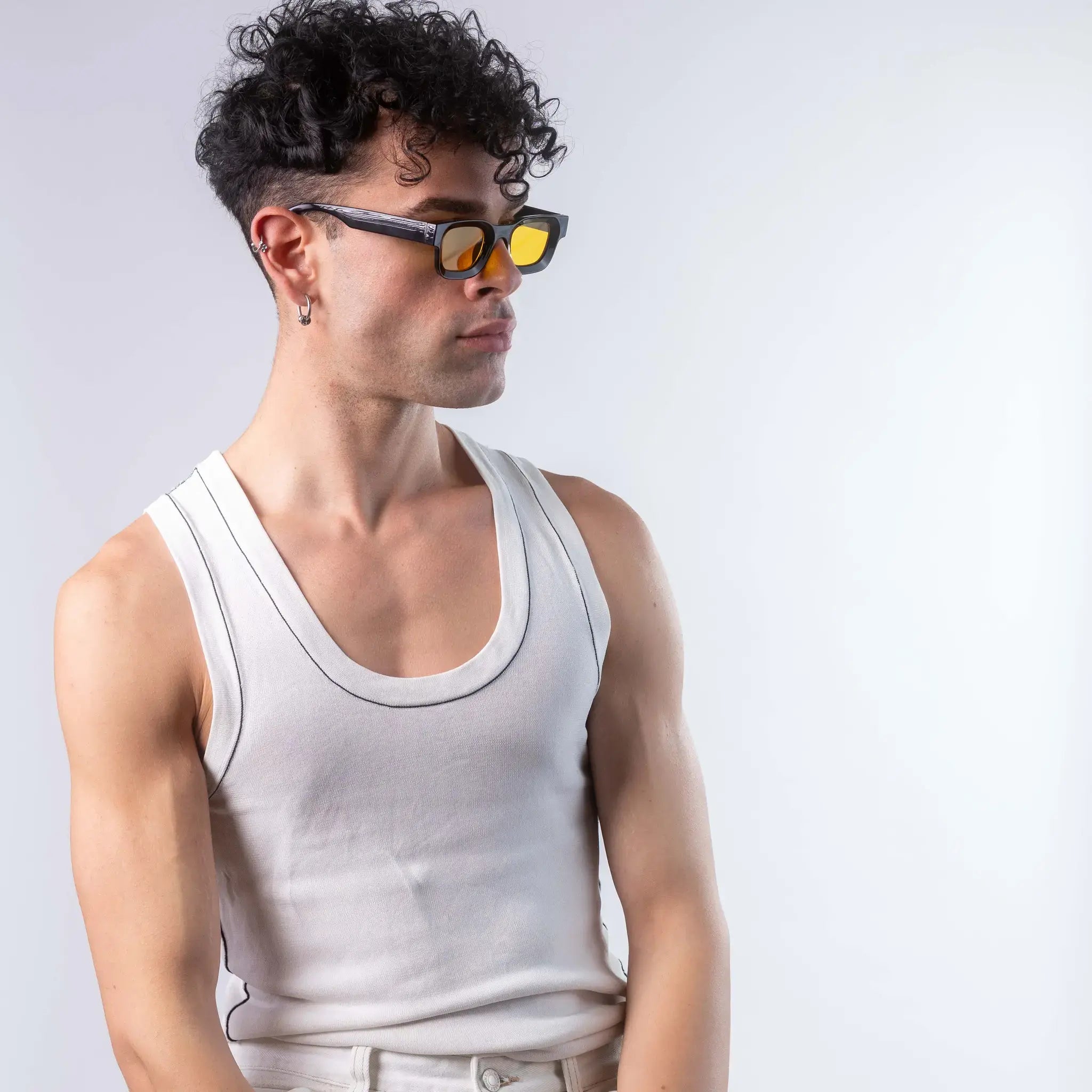 A male model wearing Exposure Sunglasses polarized sunglasses with black frames and yellow lenses, posing against a white background.