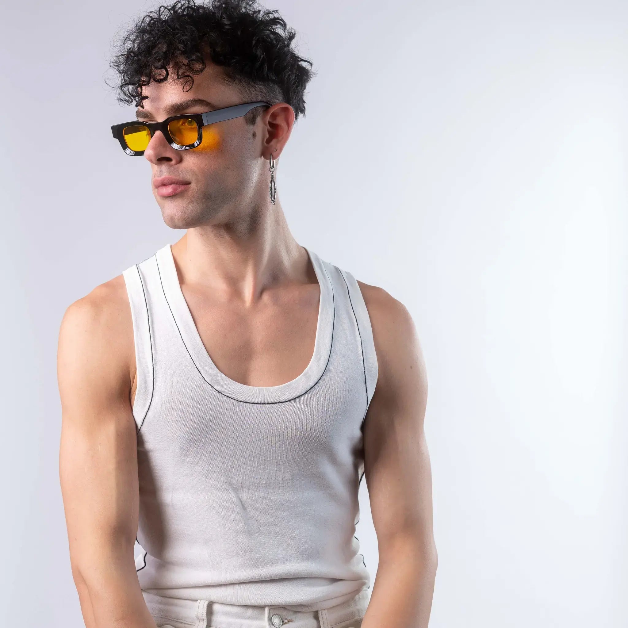 A male model wearing Exposure Sunglasses polarized sunglasses with black frames and yellow lenses, posing against a white background.