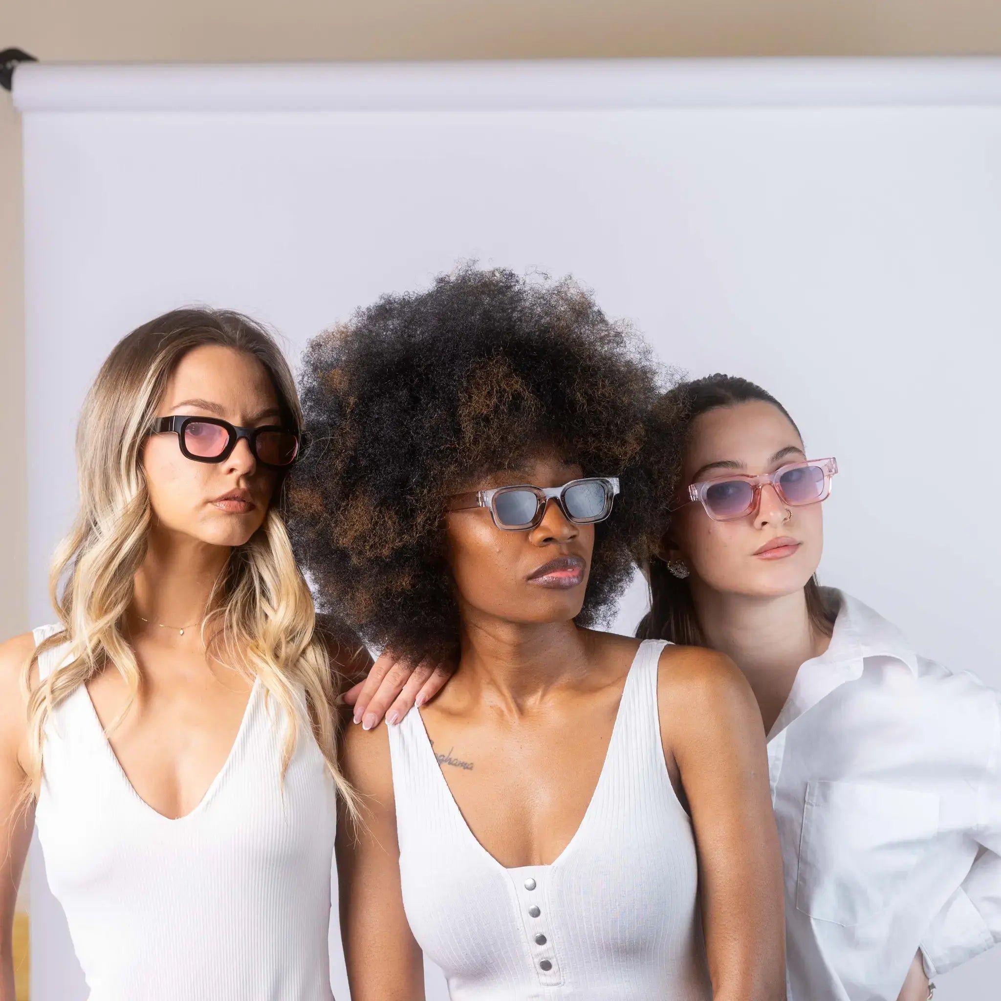 Three models wearing Exposure Sunglasses polarized sunglasses with black frames and tinted lenses, posing against a white background.