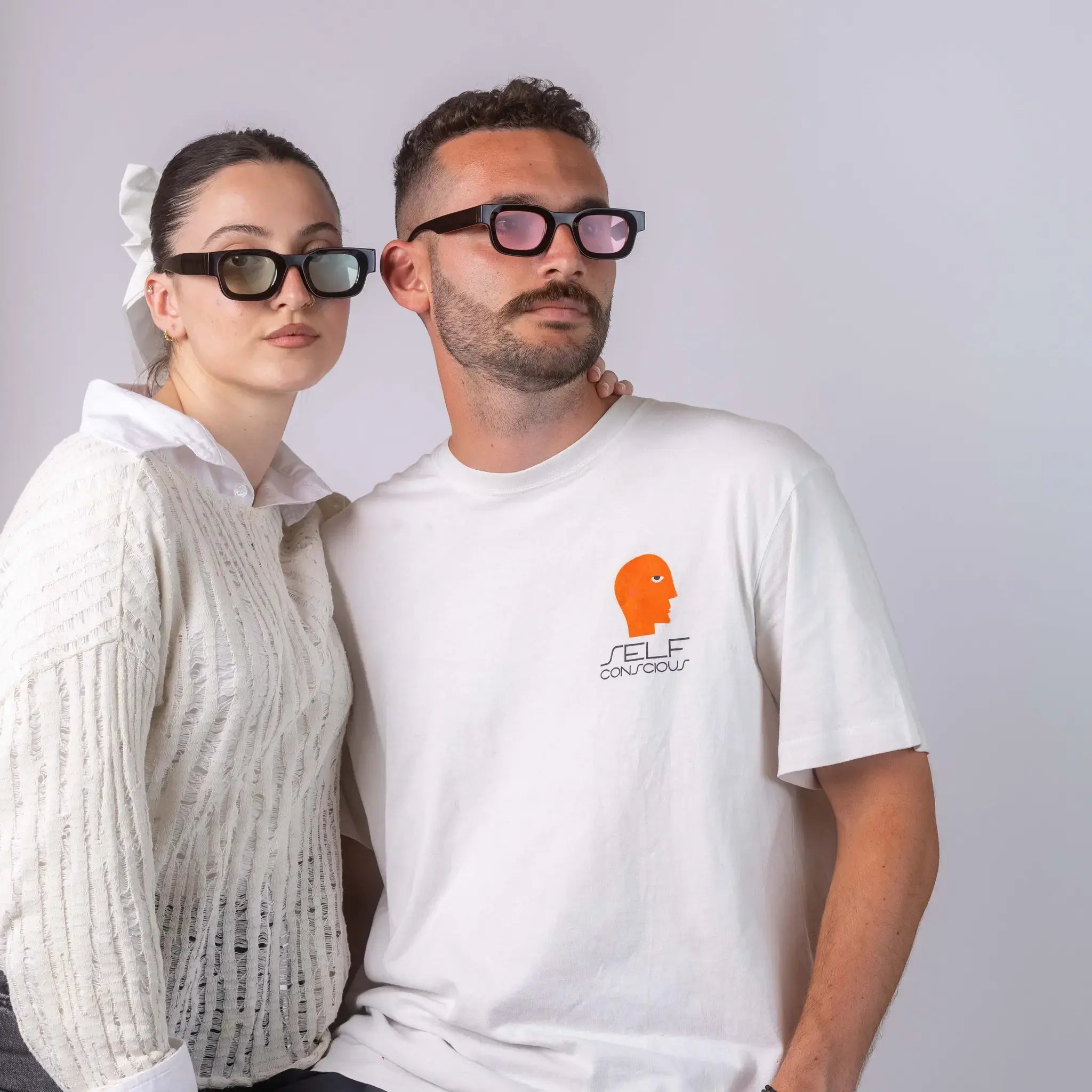 Two models wearing Exposure Sunglasses polarized sunglasses with black frames and tinted lenses, posing against a white background.