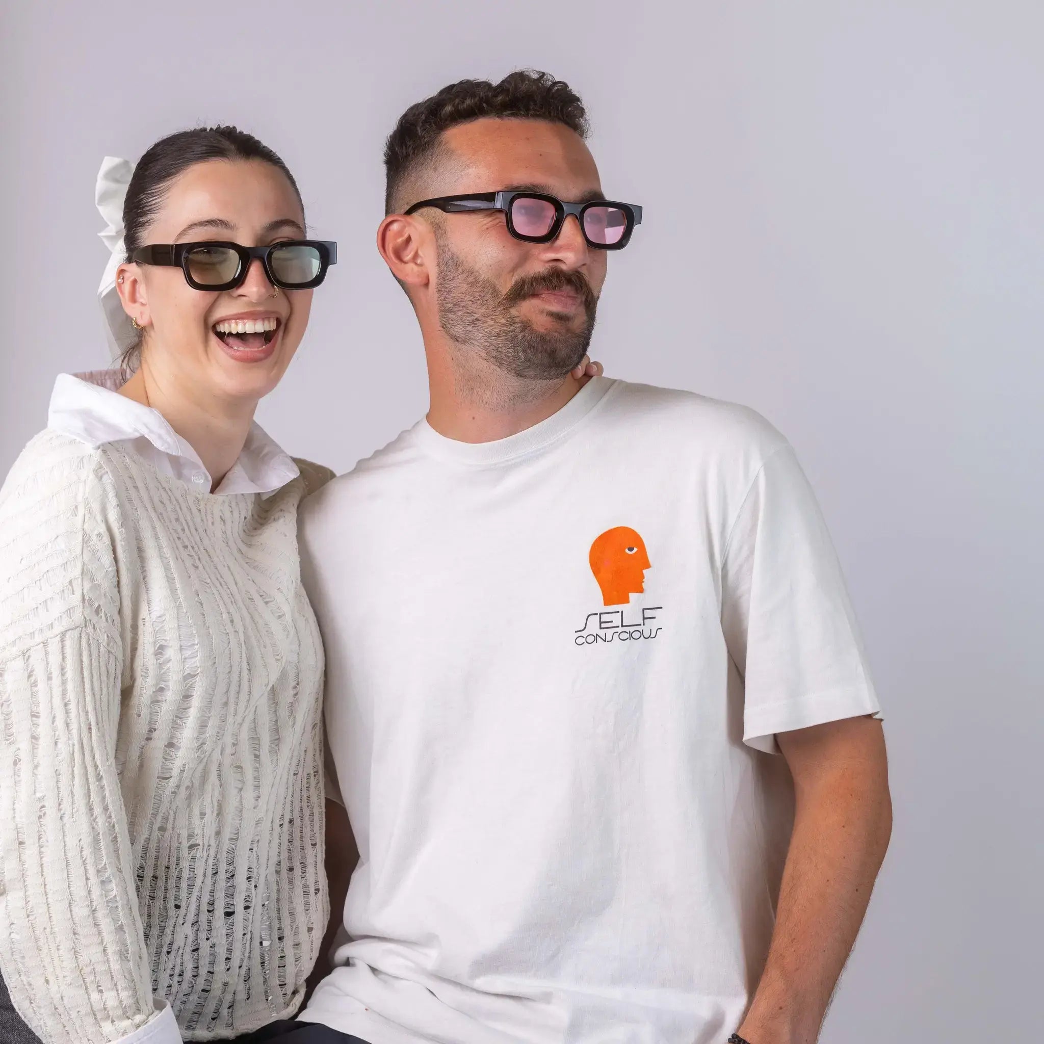 Two models wearing Exposure Sunglasses polarized sunglasses with black frames and tinted lenses, posing against a white background.