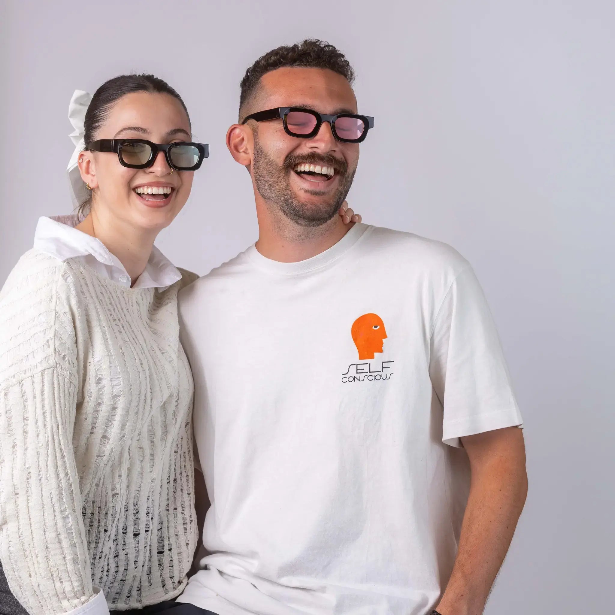 Two models wearing Exposure Sunglasses polarized sunglasses with black frames and tinted lenses, posing against a white background.