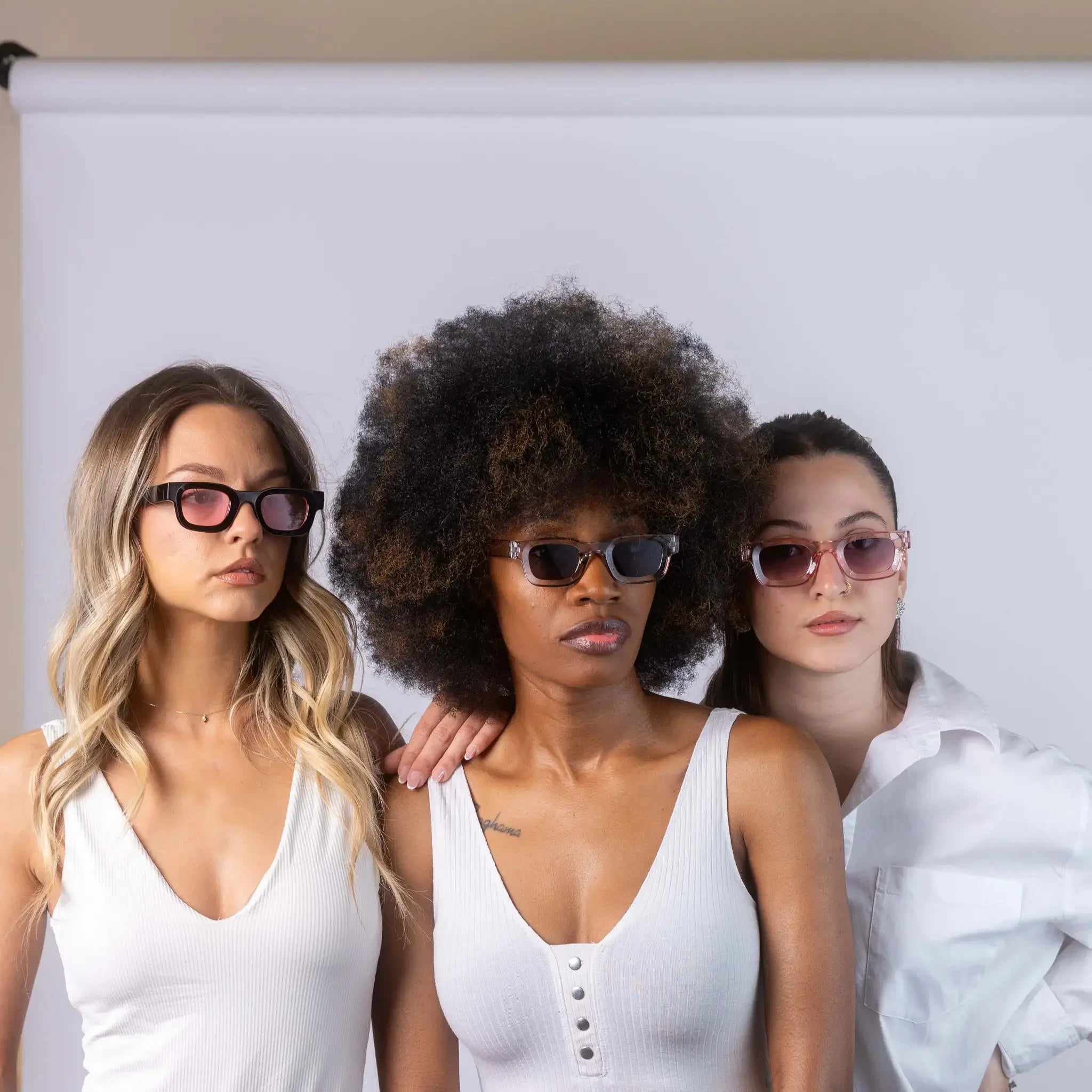 Three models wearing Exposure Sunglasses polarized sunglasses with black frames and tinted lenses, posing against a white background.