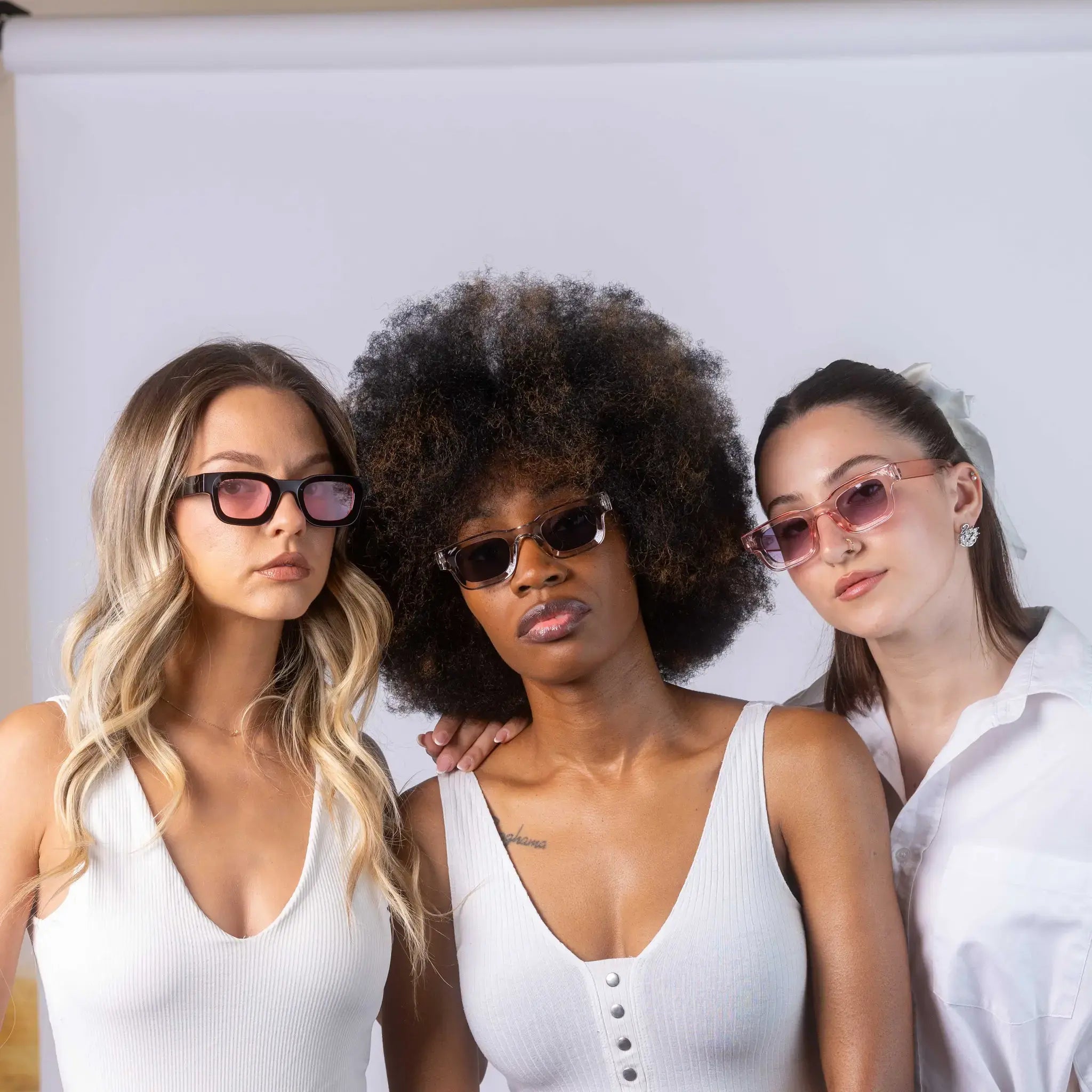 Three models wearing Exposure Sunglasses polarized sunglasses with black frames and tinted lenses, posing against a white background.