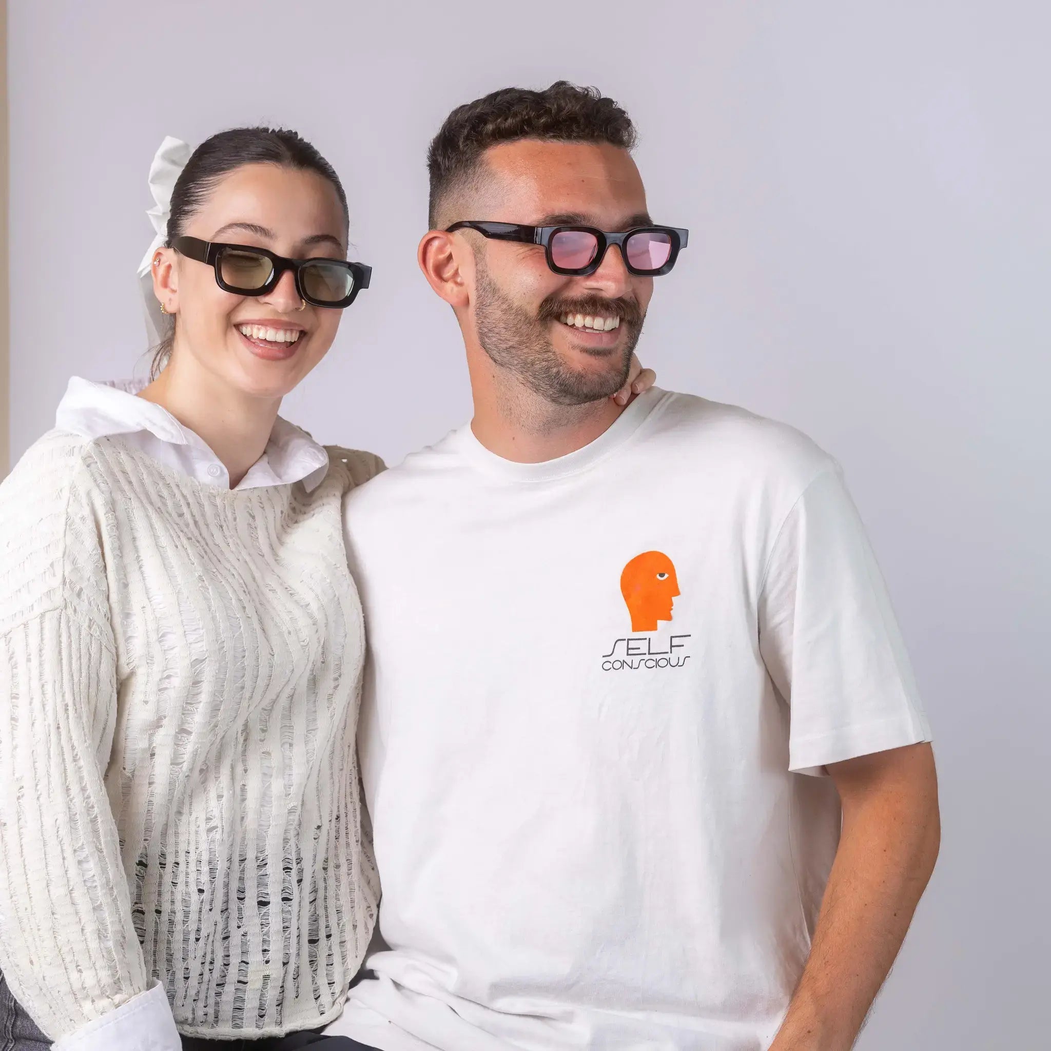 Two models wearing Exposure Sunglasses polarized sunglasses with black frames and tinted lenses, posing against a white background.