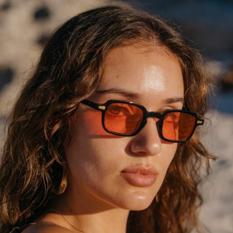 Τετράγωνα Γυαλιά ηλίου Luminous της Exposure Sunglasses με προστασία UV400 με μαύρο σκελετό και κόκκινο φακό φορεμένα.